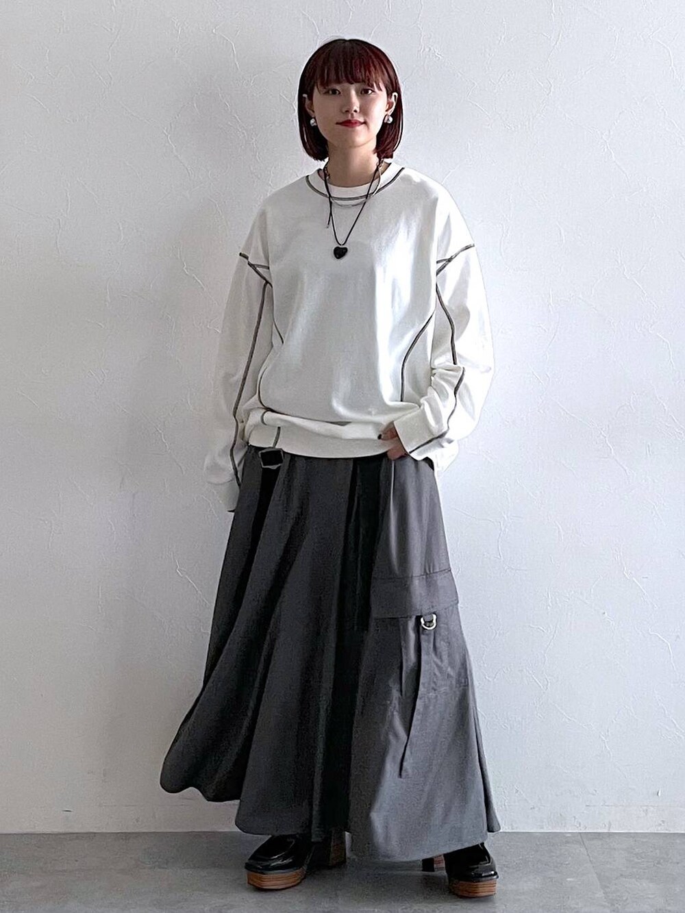 ホワイト系のスウェット、ブラック系のローファー、グレー系のジャンパースカートを着用したレディースの秋コーディネートの2枚目の写真
