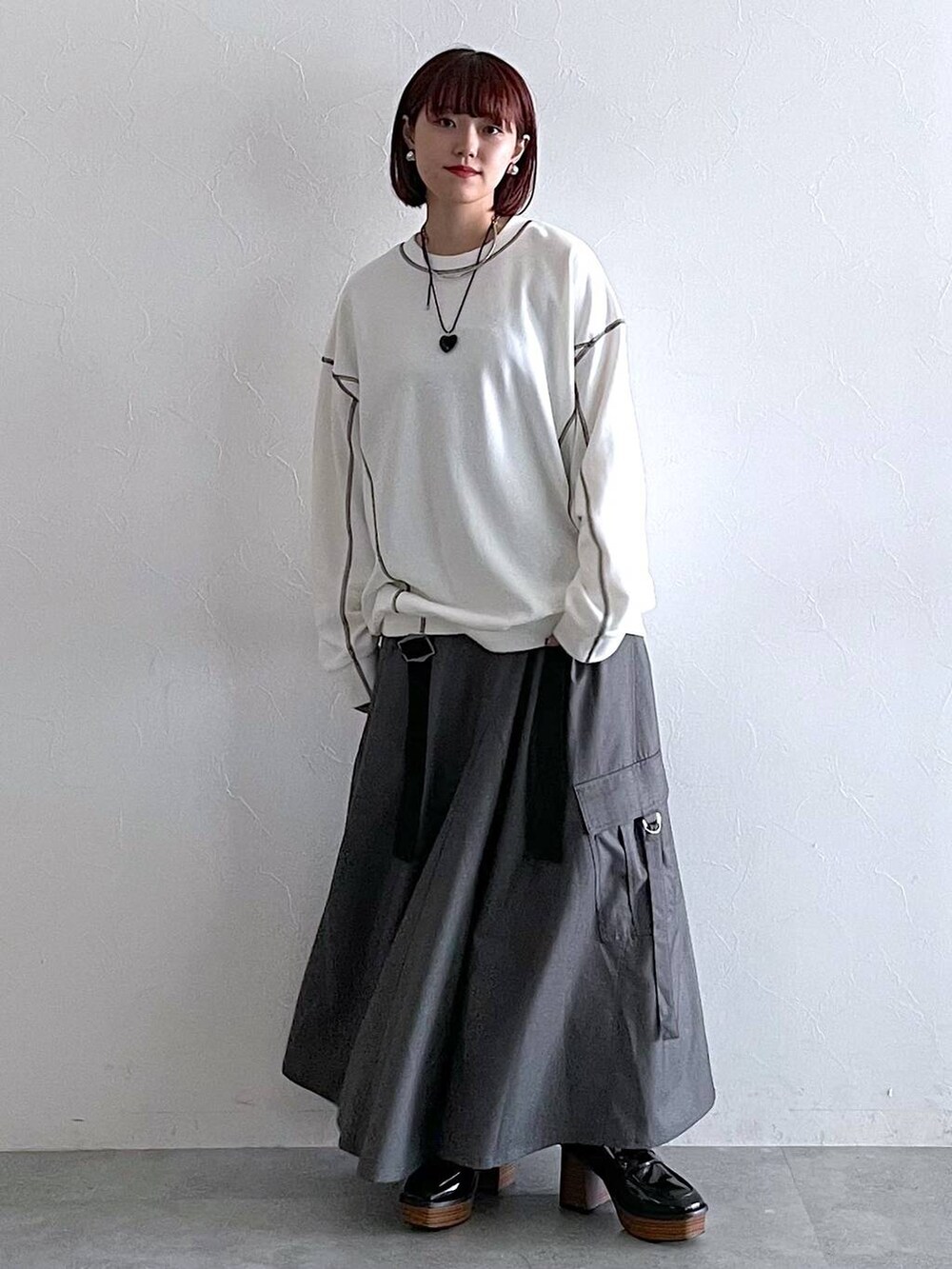 ホワイト系のスウェット、ブラック系のローファー、グレー系のジャンパースカートを着用したレディースの秋コーディネートの7枚目の写真