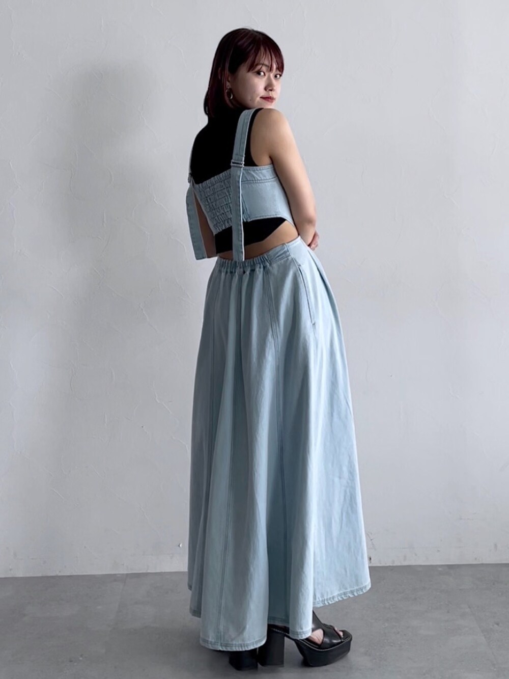 ブラック系のトップス、ブルー系のジャンパースカート、ブラック系のシューズを着用したレディースの春コーディネートの3枚目の写真