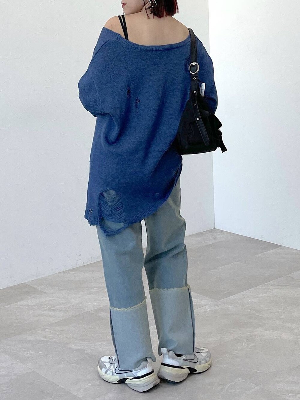 ブラック系のショルダーバッグ、ブルー系のニット/セーター、ブルー系のデニムパンツを着用したレディースの春コーディネートの2枚目の写真