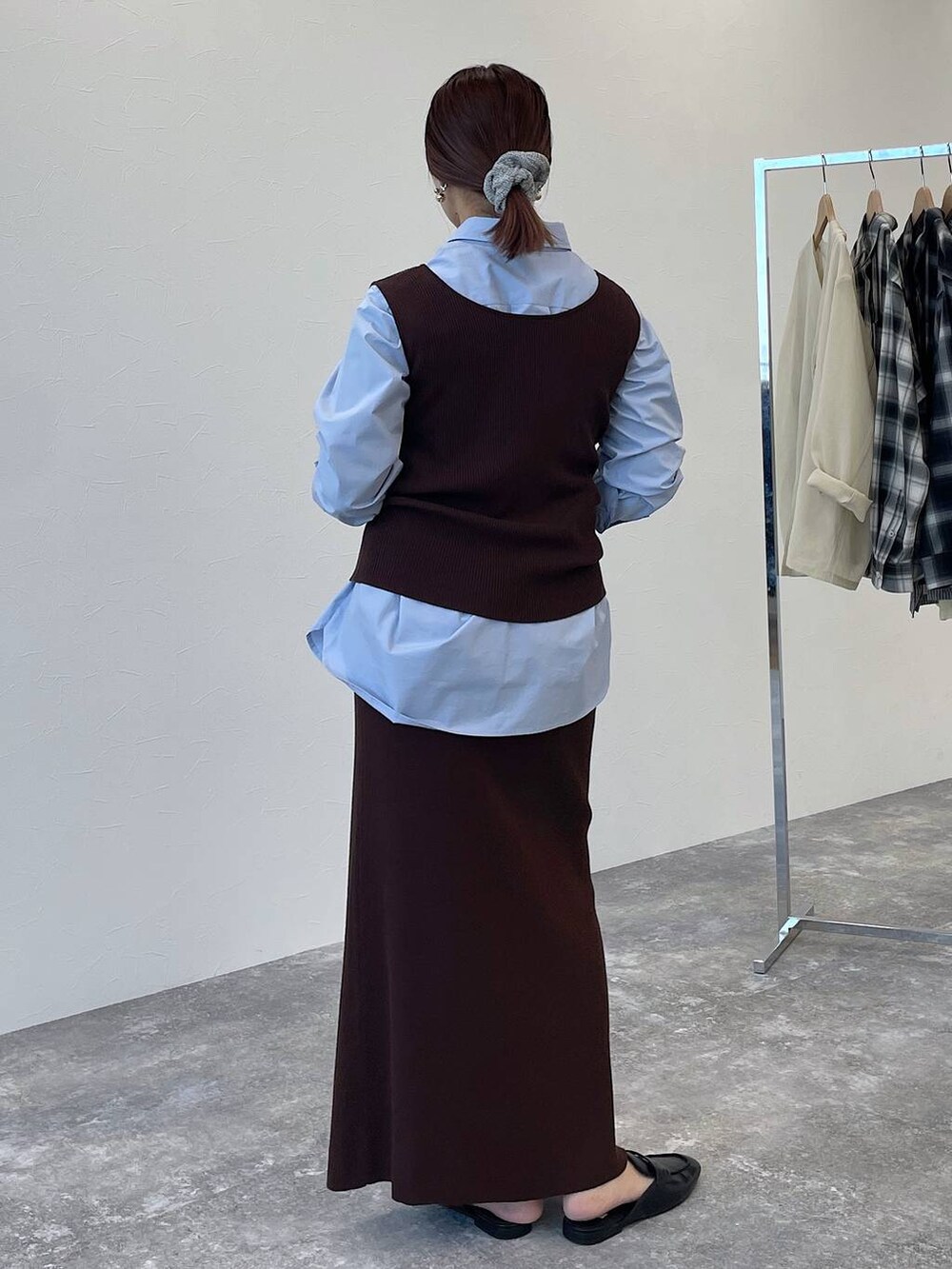 ブラウン系のニット/セーター、ブラウン系のスカート、ブルー系のシャツ/ブラウスを着用したレディースの秋コーディネートの4枚目の写真
