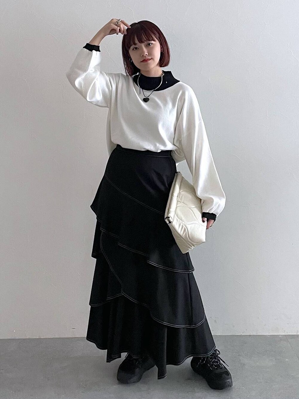 ホワイト系のニット/セーター、ホワイト系のクラッチバッグ、ブラック系のスカートを着用したレディースの秋コーディネートの4枚目の写真