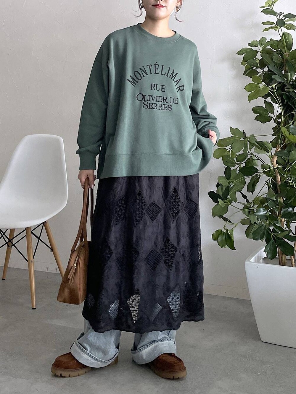 グリーン系のスウェット、ブルー系のデニムパンツ、ブラック系のスカートを着用したレディースの秋コーディネートの4枚目の写真