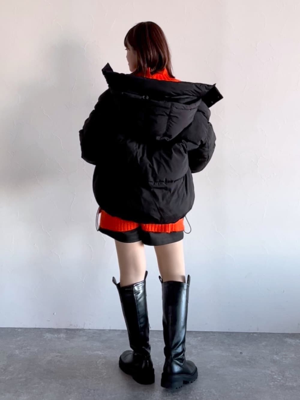 オレンジ系のニット/セーター、ブラック系のブルゾン、ブラック系のその他パンツを着用したレディースの冬コーディネートの3枚目の写真