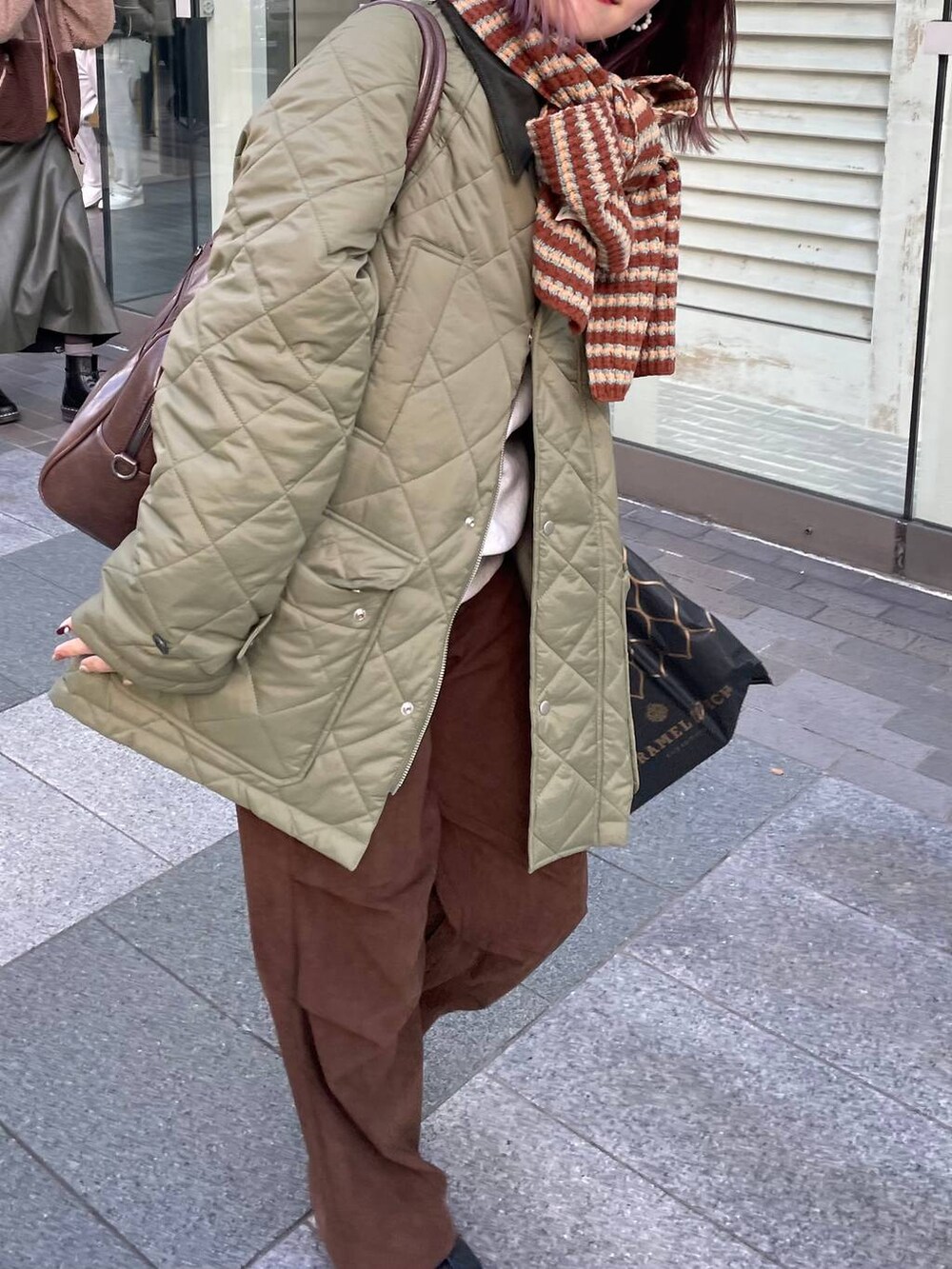 ブラウン系のその他パンツ、ブラウン系のボストンバッグ、グリーン系のダウンジャケット/コートを着用したレディースの冬コーディネートの2枚目の写真