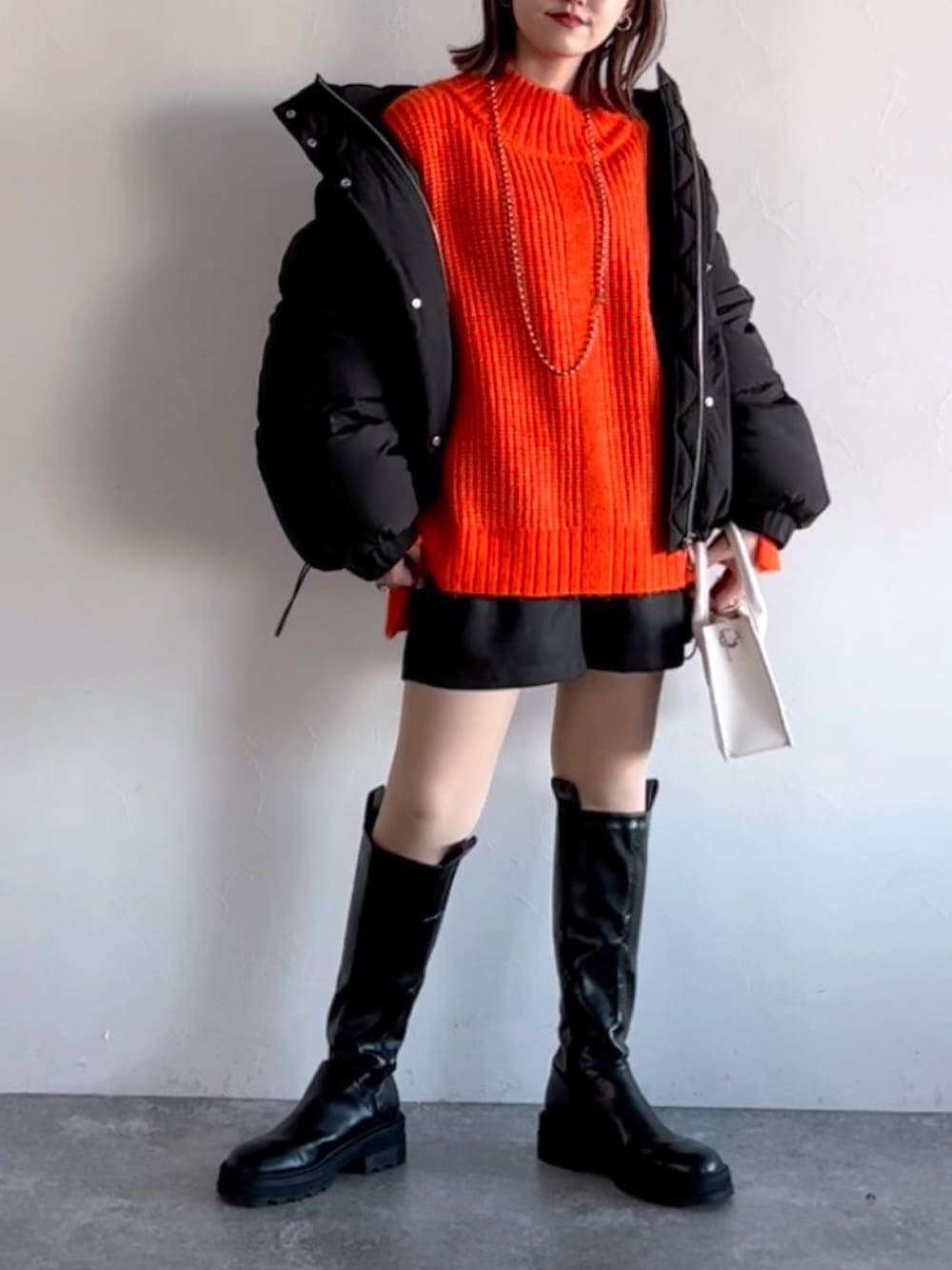 オレンジ系のニット/セーター、ブラック系のブルゾン、ブラック系のその他パンツを着用したレディースの冬コーディネートの4枚目の写真