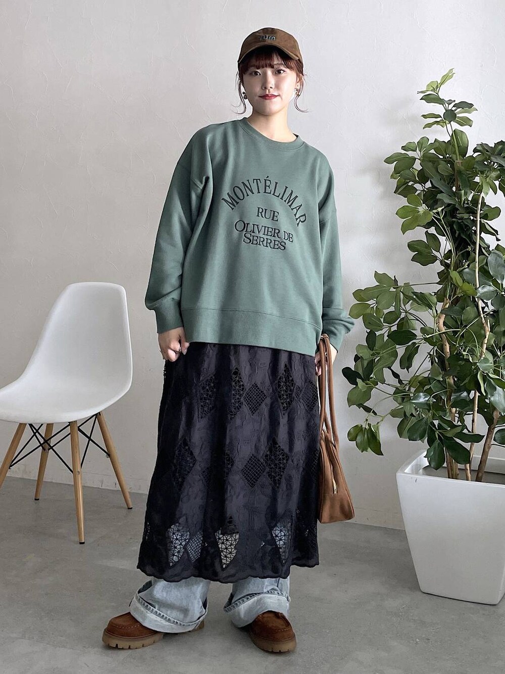 グリーン系のスウェット、ブルー系のデニムパンツ、ブラック系のスカートを着用したレディースの秋コーディネートの6枚目の写真