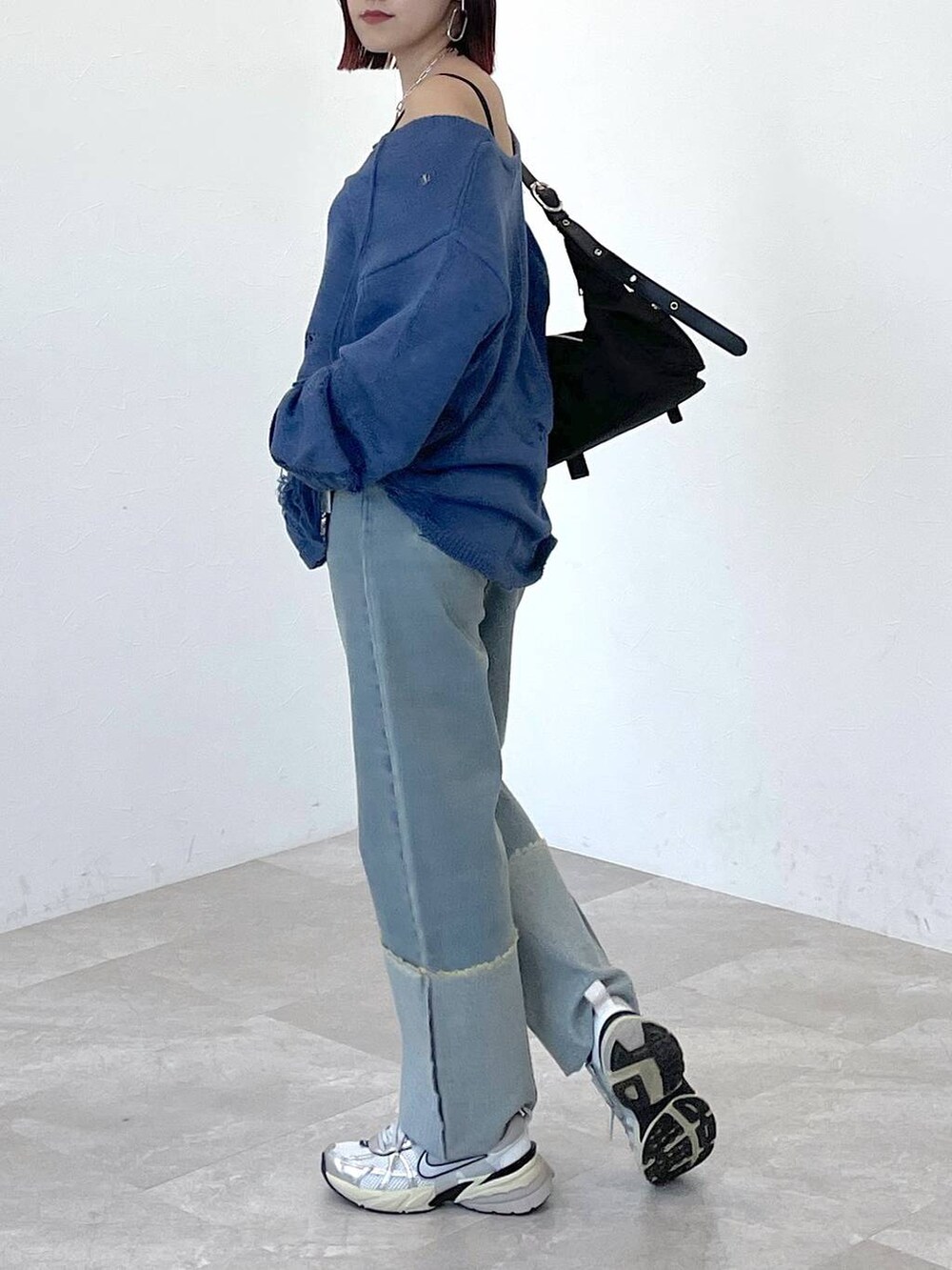 ブラック系のショルダーバッグ、ブルー系のニット/セーター、ブルー系のデニムパンツを着用したレディースの春コーディネートの4枚目の写真