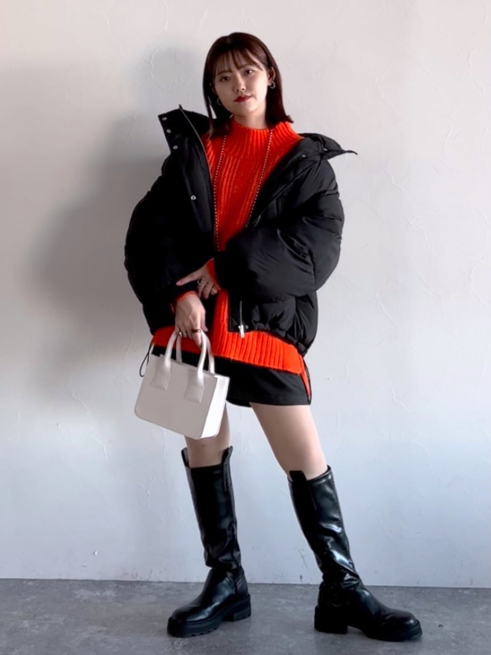 オレンジ系のニット/セーター、ブラック系のブルゾン、ブラック系のその他パンツを着用したレディースの冬コーディネートの2枚目の写真