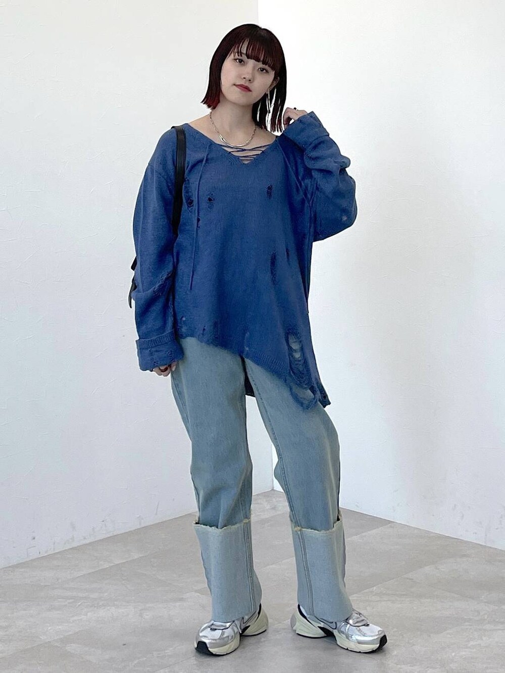 ブラック系のショルダーバッグ、ブルー系のニット/セーター、ブルー系のデニムパンツを着用したレディースの春コーディネートの6枚目の写真