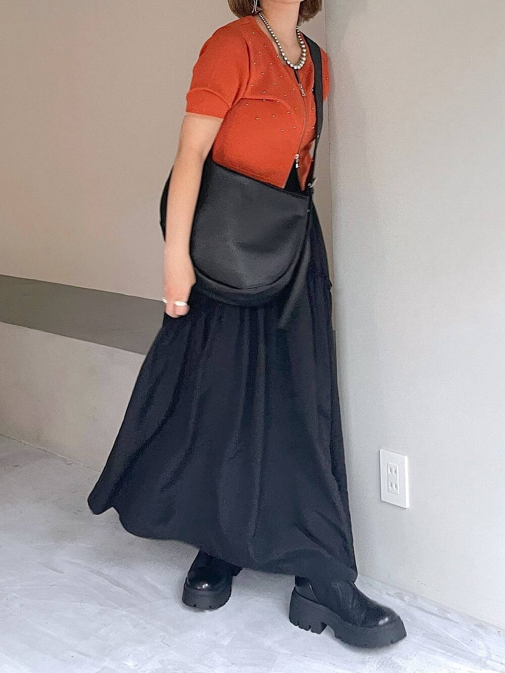 ブラック系のブーツ、ブラック系のスカート、ブラック系のショルダーバッグを着用したレディースの夏コーディネートの2枚目の写真