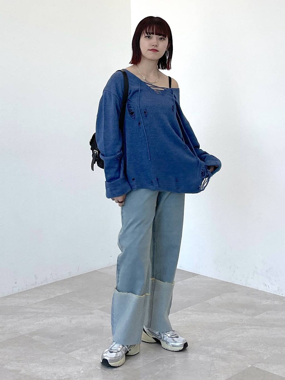 ブラック系のショルダーバッグ、ブルー系のニット/セーター、ブルー系のデニムパンツを着用したレディースの春コーディネートの7枚目の写真