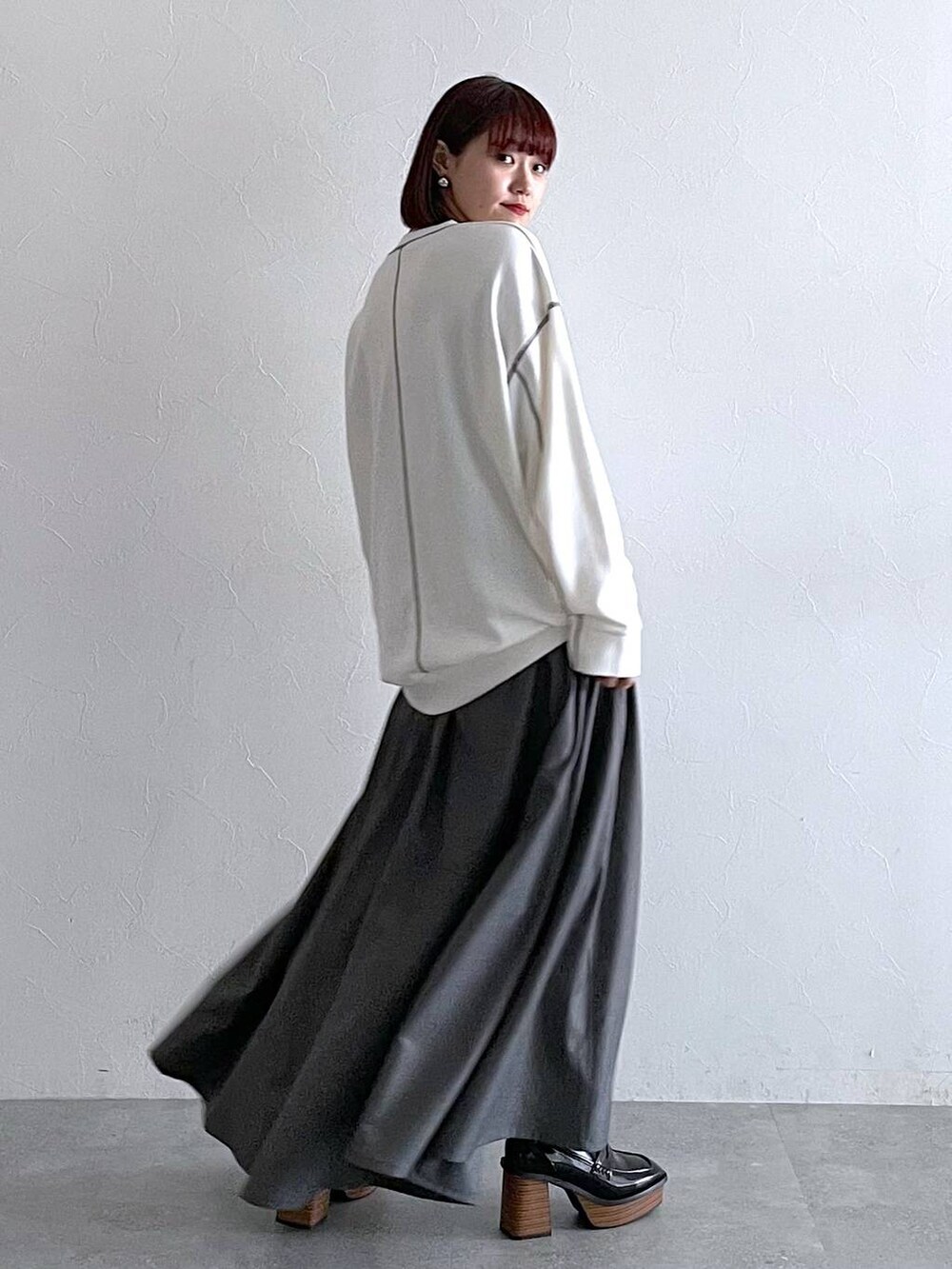 ホワイト系のスウェット、ブラック系のローファー、グレー系のジャンパースカートを着用したレディースの秋コーディネートの3枚目の写真