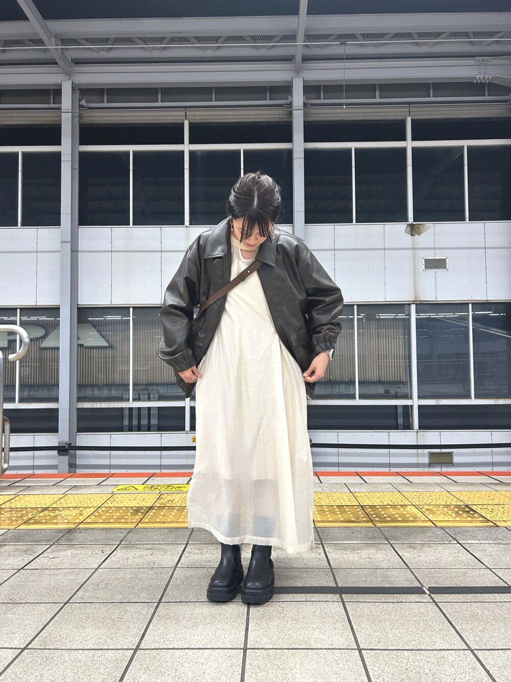 ブラウン系のブルゾン、ホワイト系のワンピース、ブラック系のブーツを着用したレディースの秋コーディネートの2枚目の写真