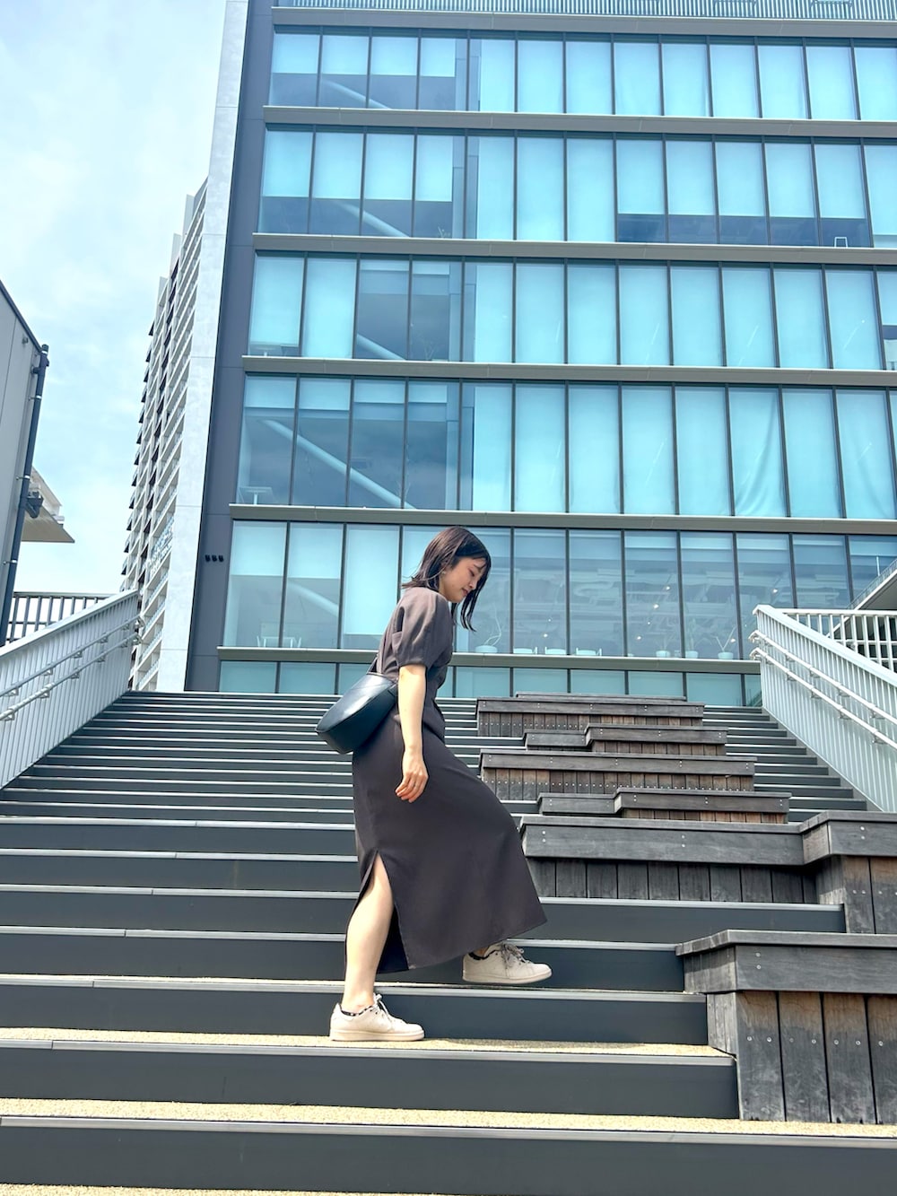 グレー系のワンピース、ピンク系のスニーカーを着用したレディースの夏コーディネートの3枚目の写真