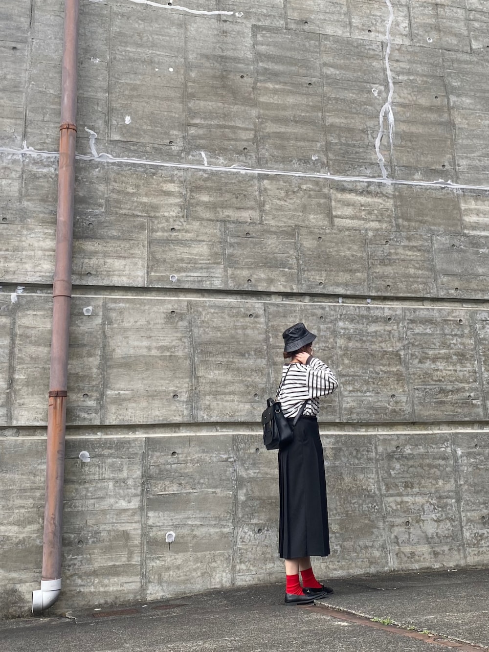 ブラック系のバックパック/リュック、ブラック系のTシャツ/カットソー、ブラック系のローファーを着用したレディースの春コーディネートの2枚目の写真