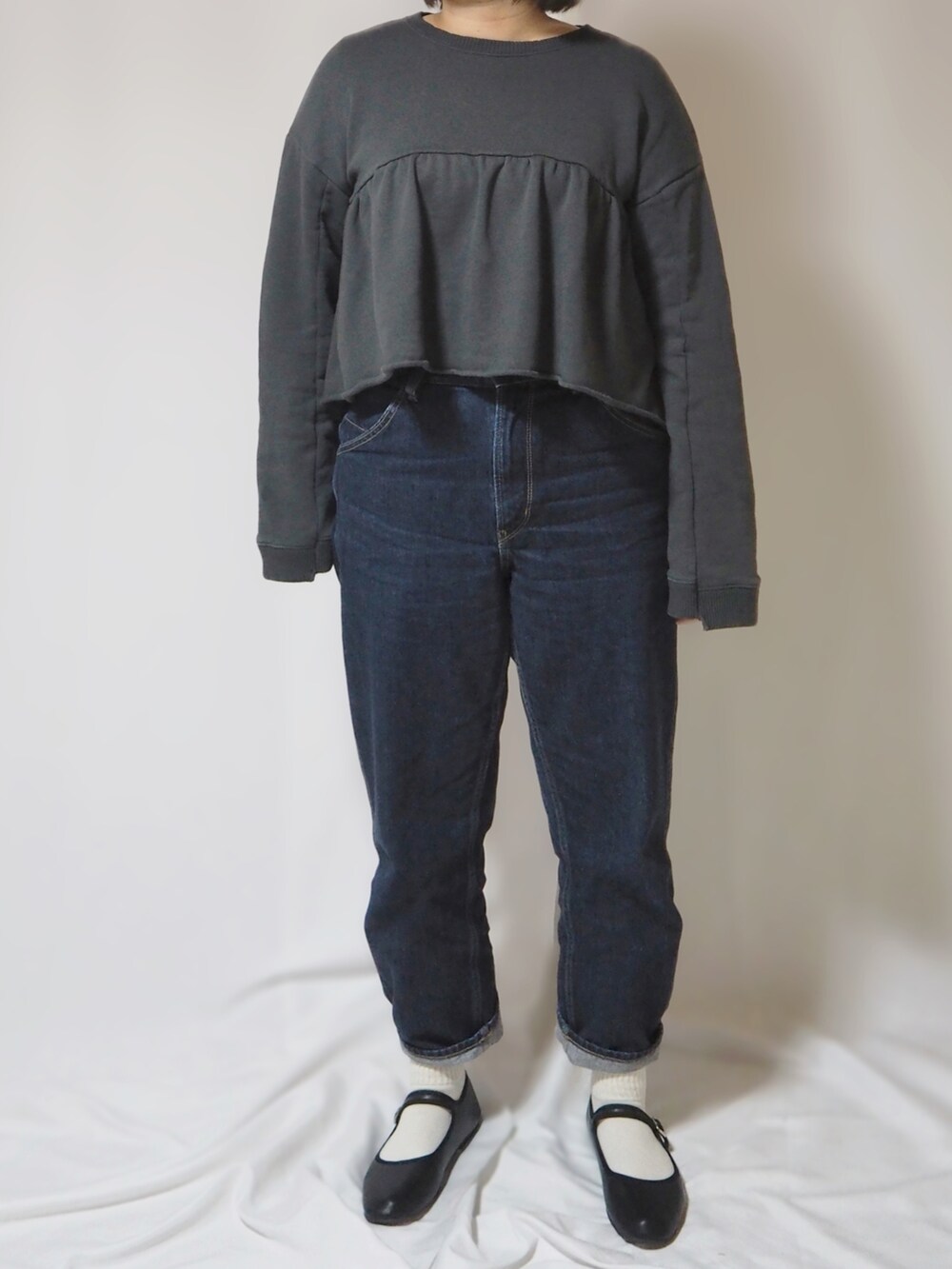 グリーン系のトレンチコート、グレー系のスウェット、ブルー系のデニムパンツを着用したレディースの冬コーディネートの2枚目の写真