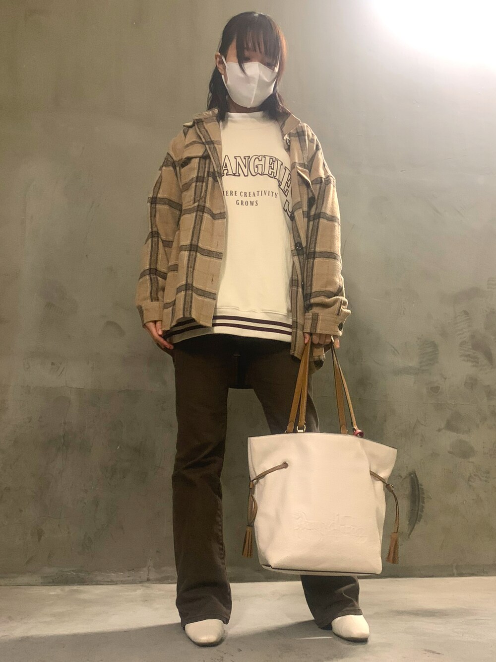 ベージュ系のスウェット、ベージュ系のトートバッグ、ブラウン系のデニムパンツを着用したレディースの秋コーディネートの2枚目の写真