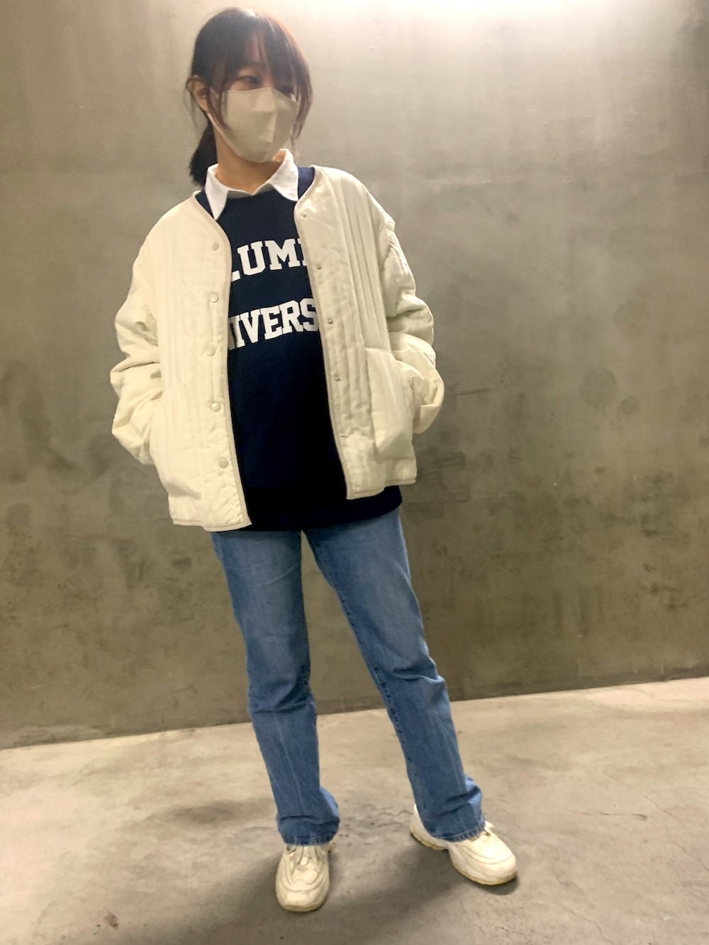 ブラック系のショルダーバッグ、ブルー系のデニムパンツ、ホワイト系のスニーカーを着用したレディースの秋コーディネートの2枚目の写真