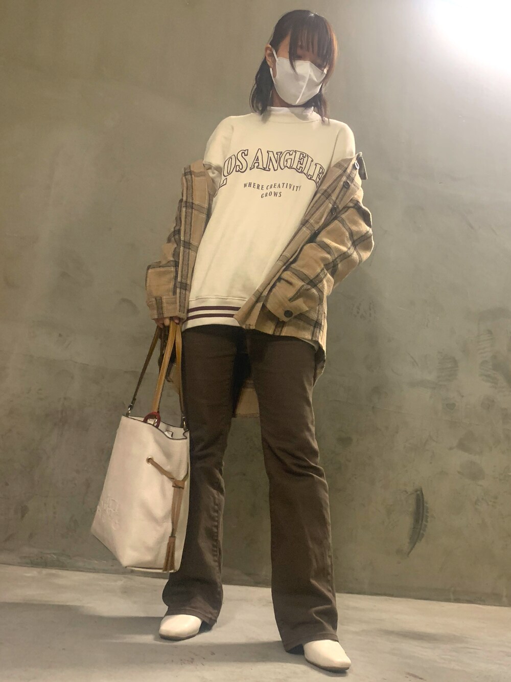 ベージュ系のスウェット、ベージュ系のトートバッグ、ブラウン系のデニムパンツを着用したレディースの秋コーディネートの3枚目の写真