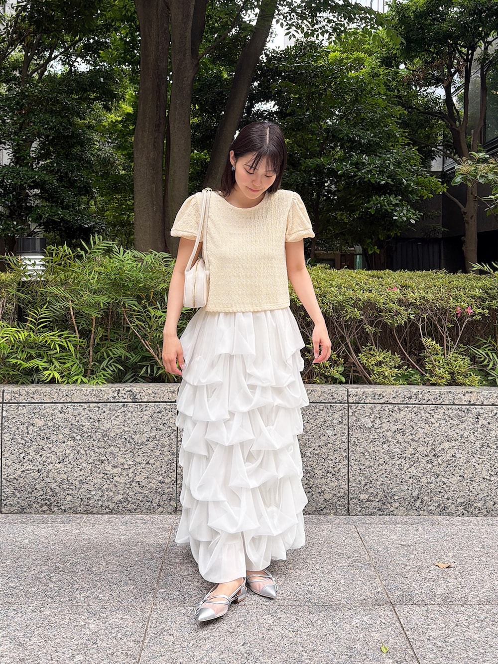 ホワイト系のスカート、イエロー系のTシャツ/カットソー、ホワイト系のショルダーバッグを着用したレディースの夏コーディネートの3枚目の写真