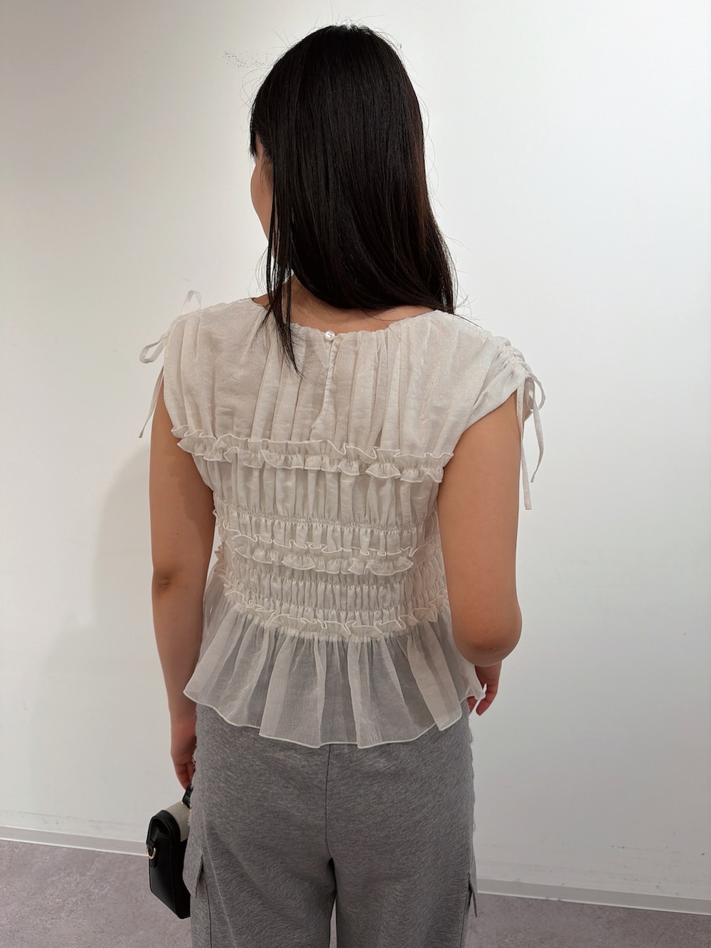 ホワイト系のシャツ/ブラウス、シルバー系のパンプス、ブラック系のショルダーバッグを着用したレディースの夏コーディネートの4枚目の写真