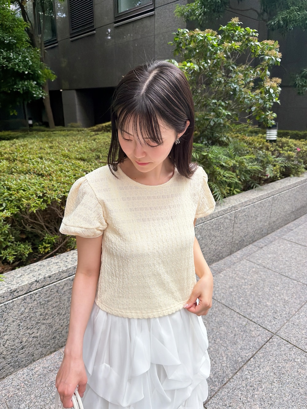ホワイト系のスカート、イエロー系のTシャツ/カットソー、ホワイト系のショルダーバッグを着用したレディースの夏コーディネートの4枚目の写真