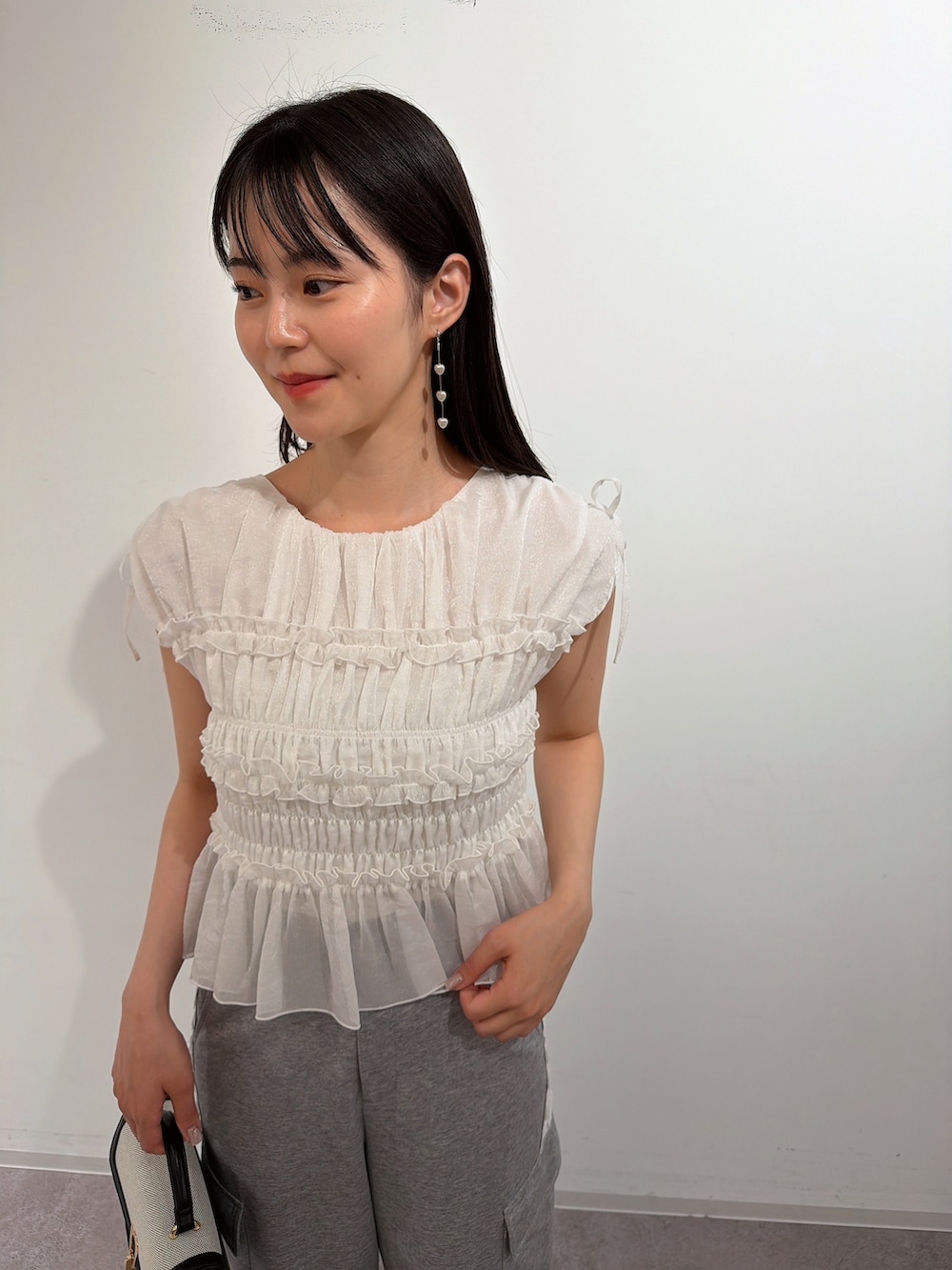 ホワイト系のシャツ/ブラウス、シルバー系のパンプス、ブラック系のショルダーバッグを着用したレディースの夏コーディネートの3枚目の写真