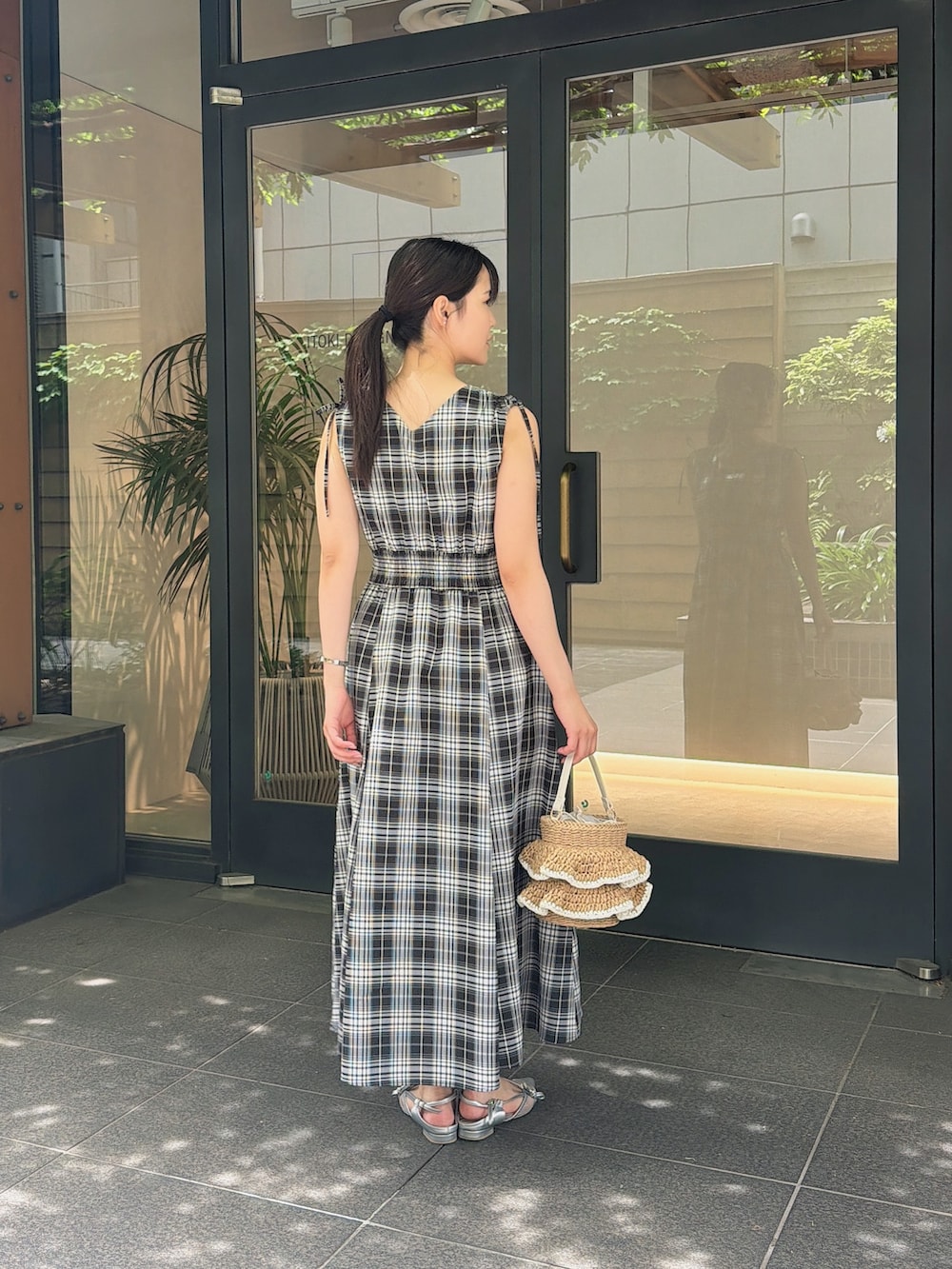 ブラック系のワンピース、シルバー系のパンプス、ベージュ系のショルダーバッグを着用したレディースの夏コーディネートの2枚目の写真