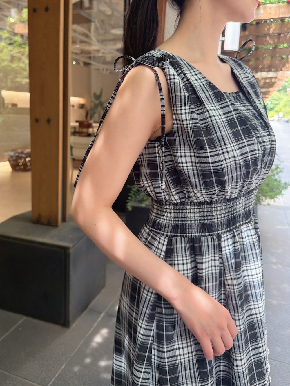 ブラック系のワンピース、シルバー系のパンプス、ベージュ系のショルダーバッグを着用したレディースの夏コーディネートの5枚目の写真