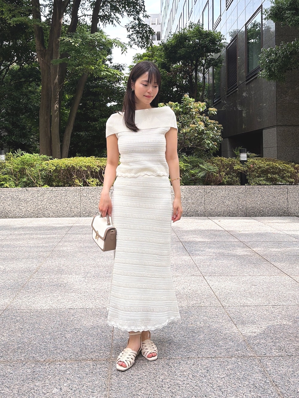 ホワイト系のワンピース、ホワイト系のパンプス、グレー系のショルダーバッグを着用したレディースの夏コーディネートの2枚目の写真