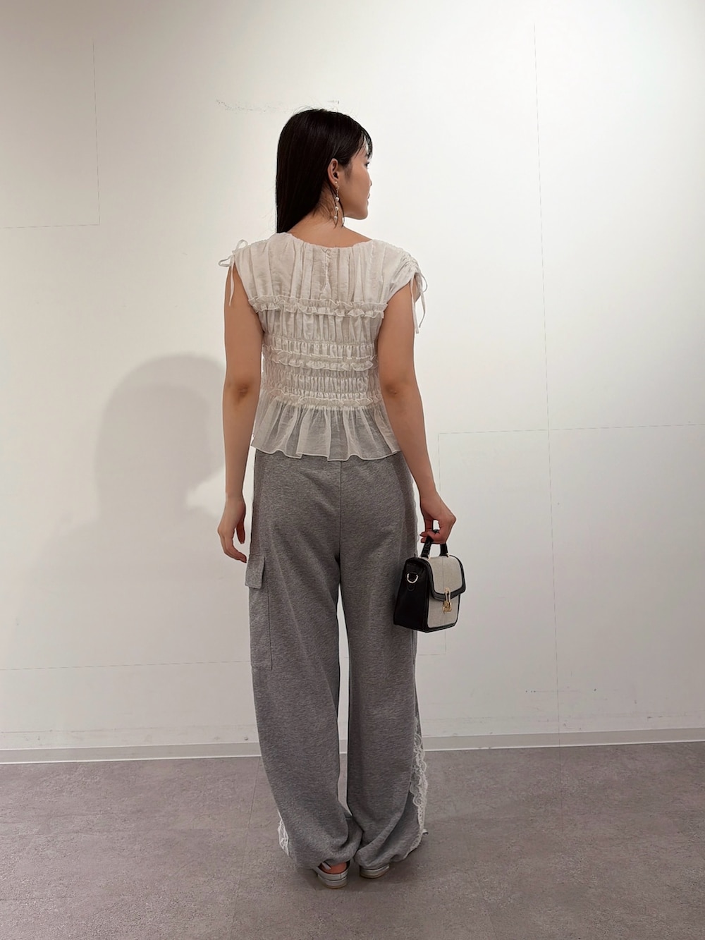 ホワイト系のシャツ/ブラウス、シルバー系のパンプス、ブラック系のショルダーバッグを着用したレディースの夏コーディネートの2枚目の写真