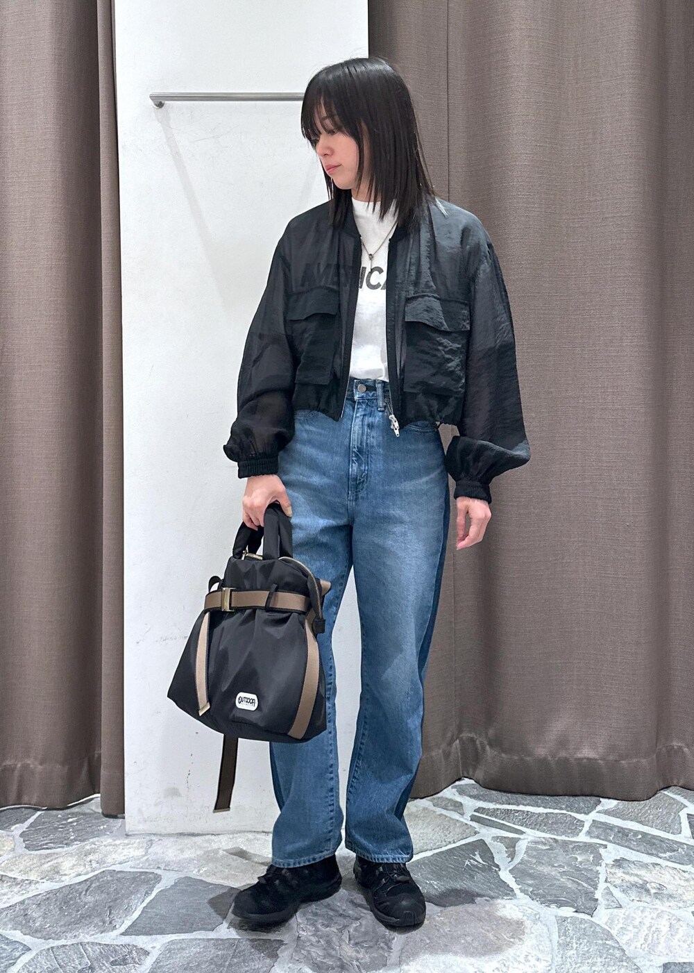 ブルー系のデニムパンツ、ブラック系のトートバッグ、ブラック系のブルゾンを着用したレディースの春コーディネートの5枚目の写真