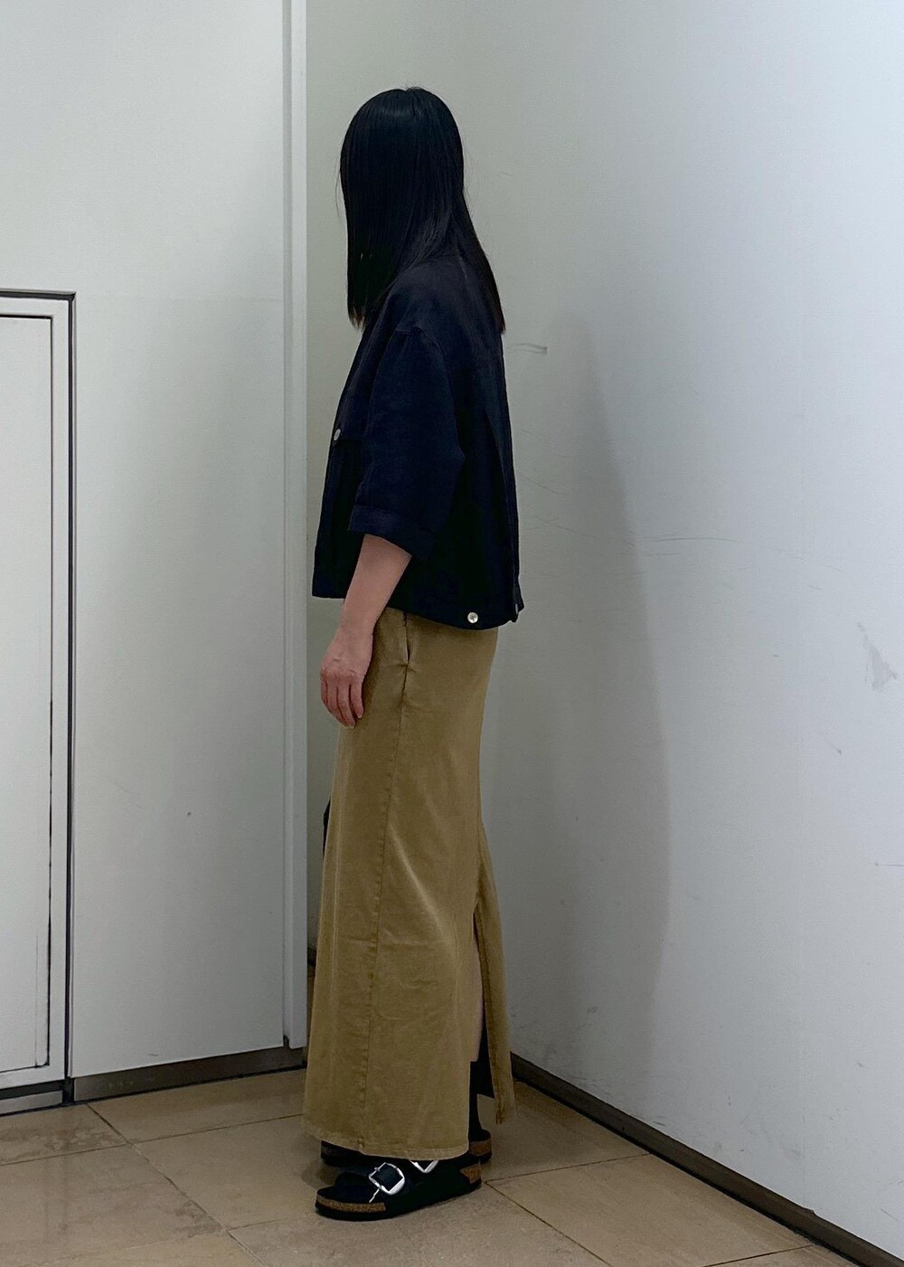 ブラック系のショルダーバッグ、ブラウン系のワンピース、ブラック系のサンダルを着用したレディースの夏コーディネートの2枚目の写真