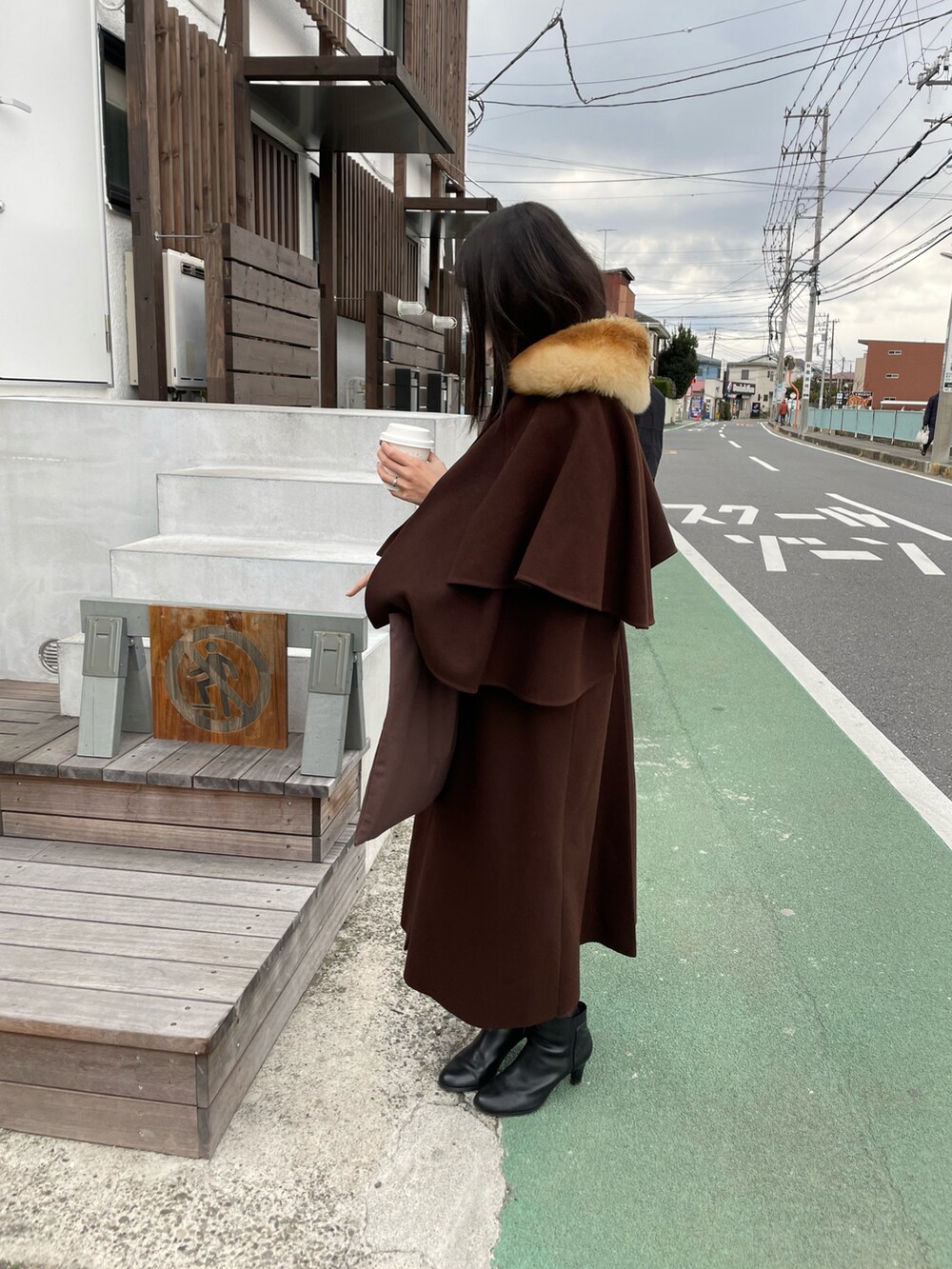 ブラウン系のトートバッグ、ブラウン系のジャケット/アウター、ブラック系のブーツを着用したレディースの冬コーディネートの2枚目の写真