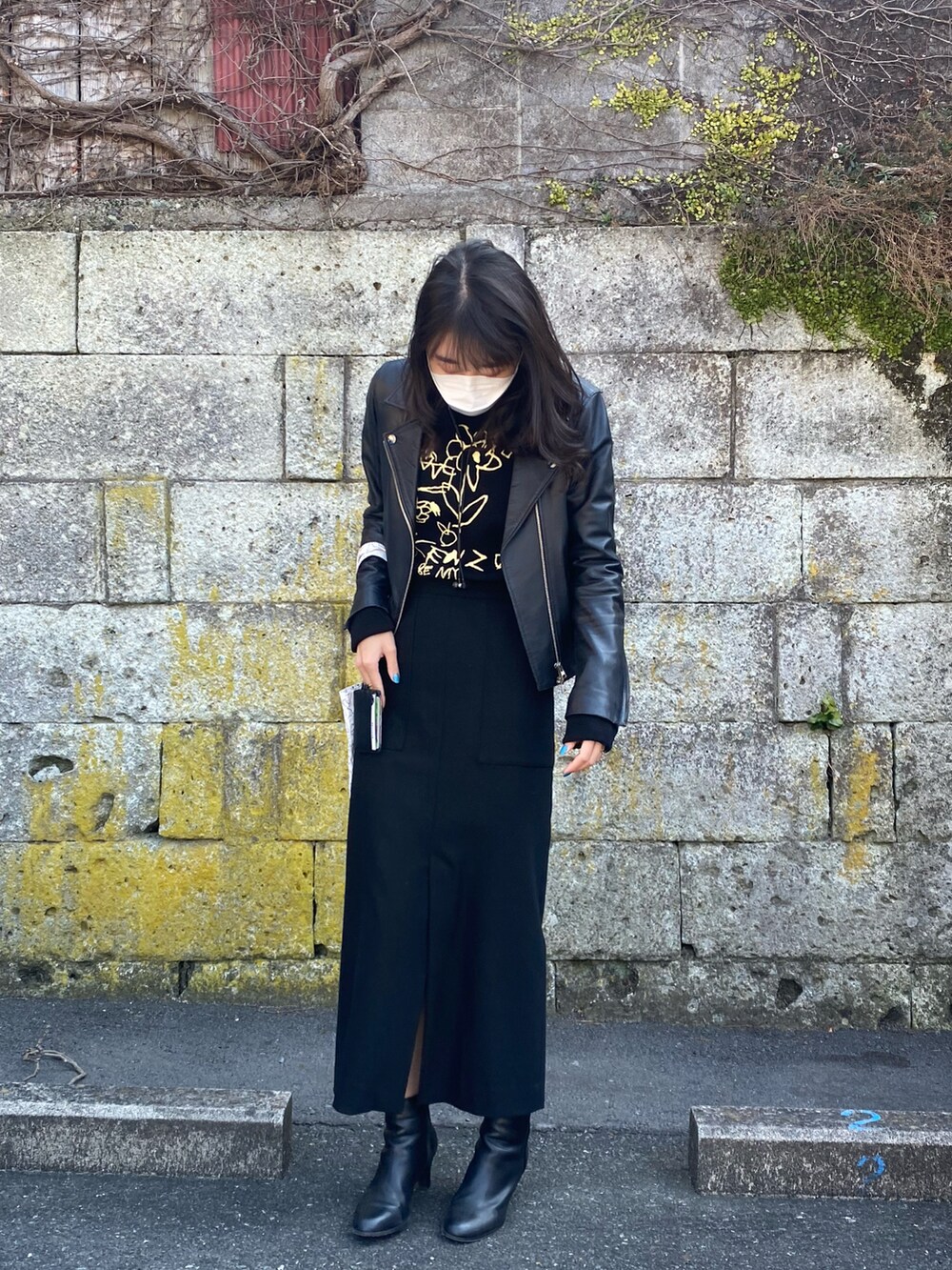 ブラック系のライダースジャケット、ブラック系のスカート、ブラック系のブーツを着用したレディースの冬コーディネートの2枚目の写真