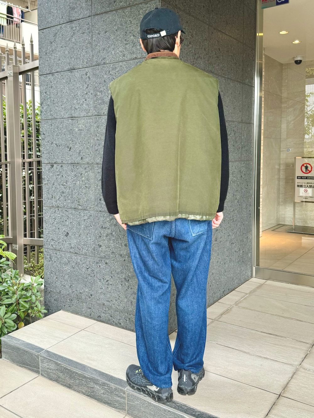 グリーン系のベスト、ブラック系のニット/セーター、ブルー系のデニムパンツを着用したメンズの冬コーディネートの2枚目の写真