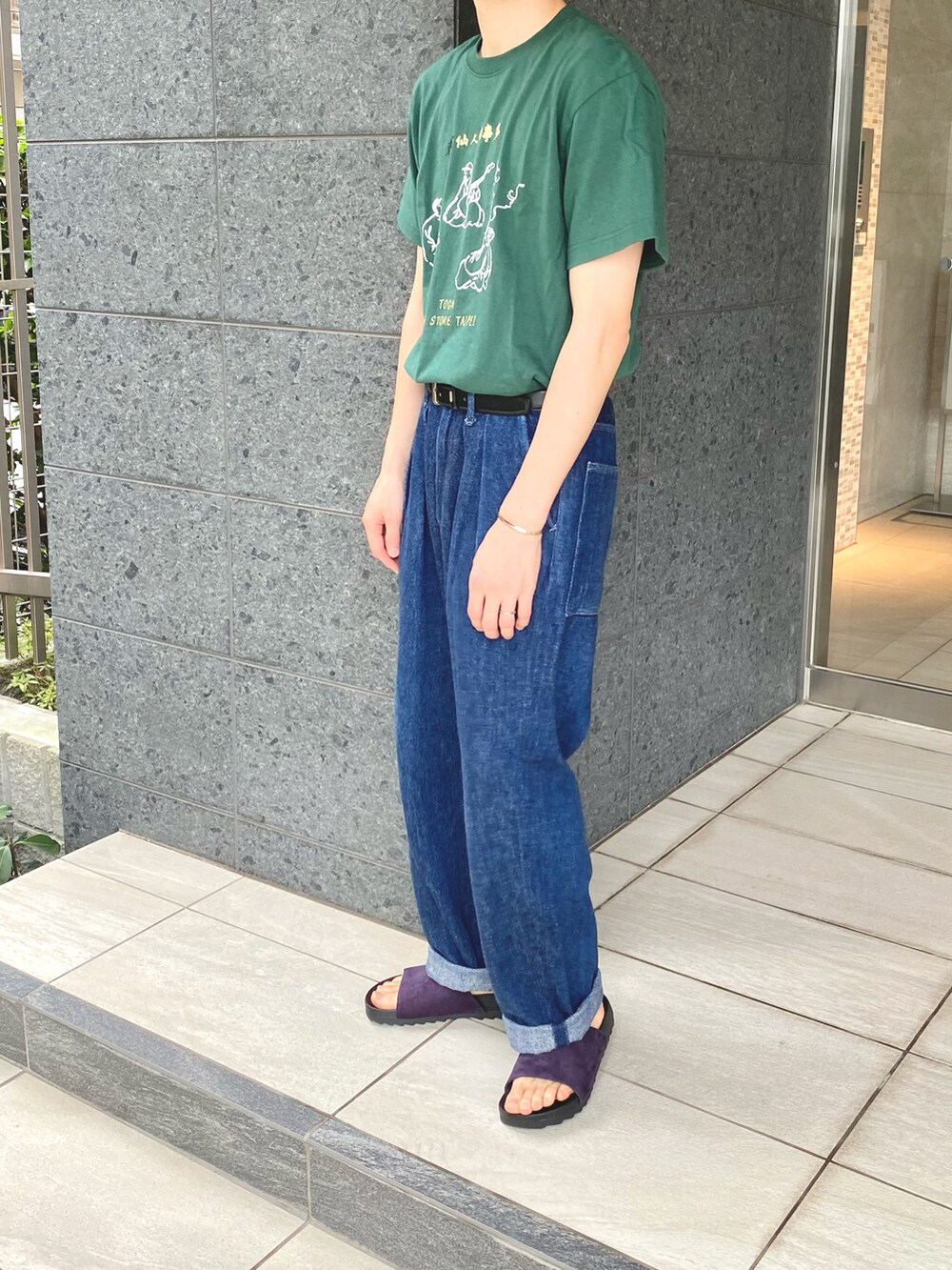 グリーン系のTシャツ/カットソー、ブルー系のデニムパンツ、シルバー系のブレスレットを着用したメンズの夏コーディネートの2枚目の写真