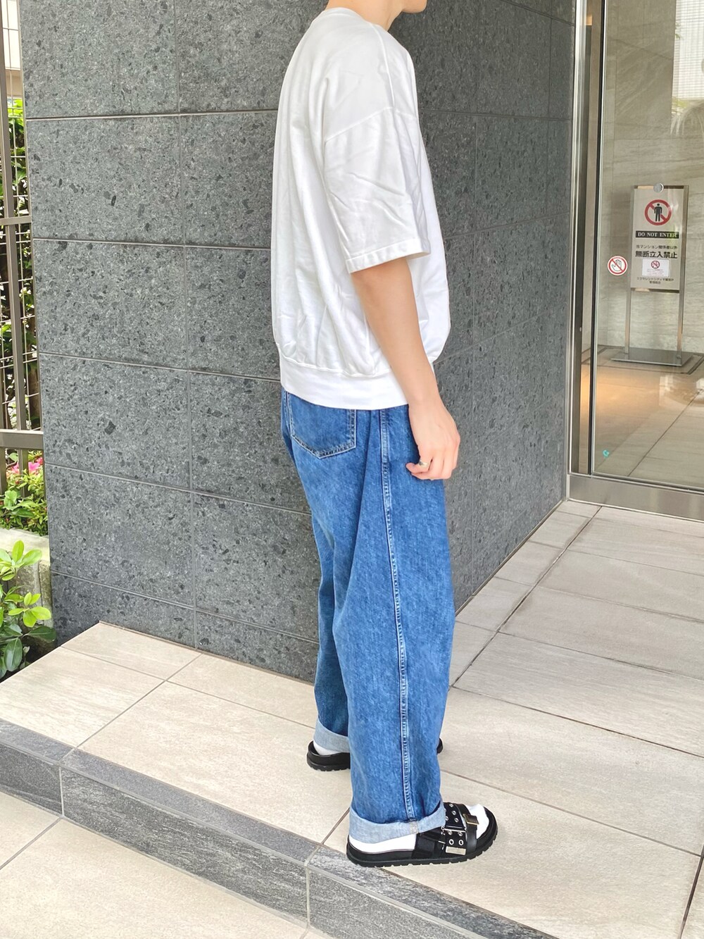 ホワイト系のTシャツ/カットソー、ブルー系のデニムパンツ、ブラック系のサンダルを着用したメンズの夏コーディネートの2枚目の写真