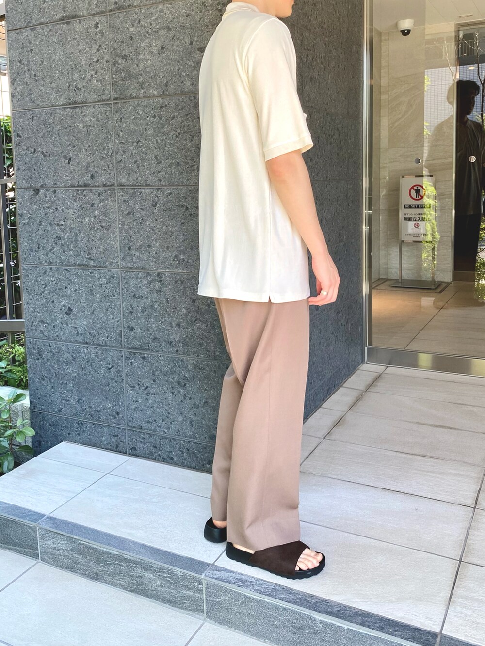 ブラウン系のパンツ、ホワイト系のポロシャツ、シルバー系のブレスレットを着用したメンズの夏コーディネートの2枚目の写真