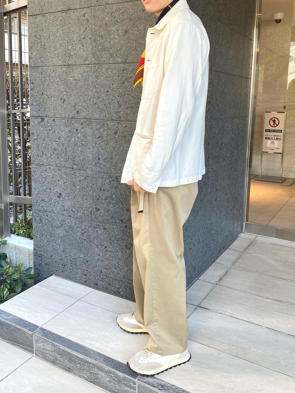 ホワイト系のブルゾン、ベージュ系のスニーカー、グリーン系のチノパンツを着用したメンズの秋コーディネートの2枚目の写真