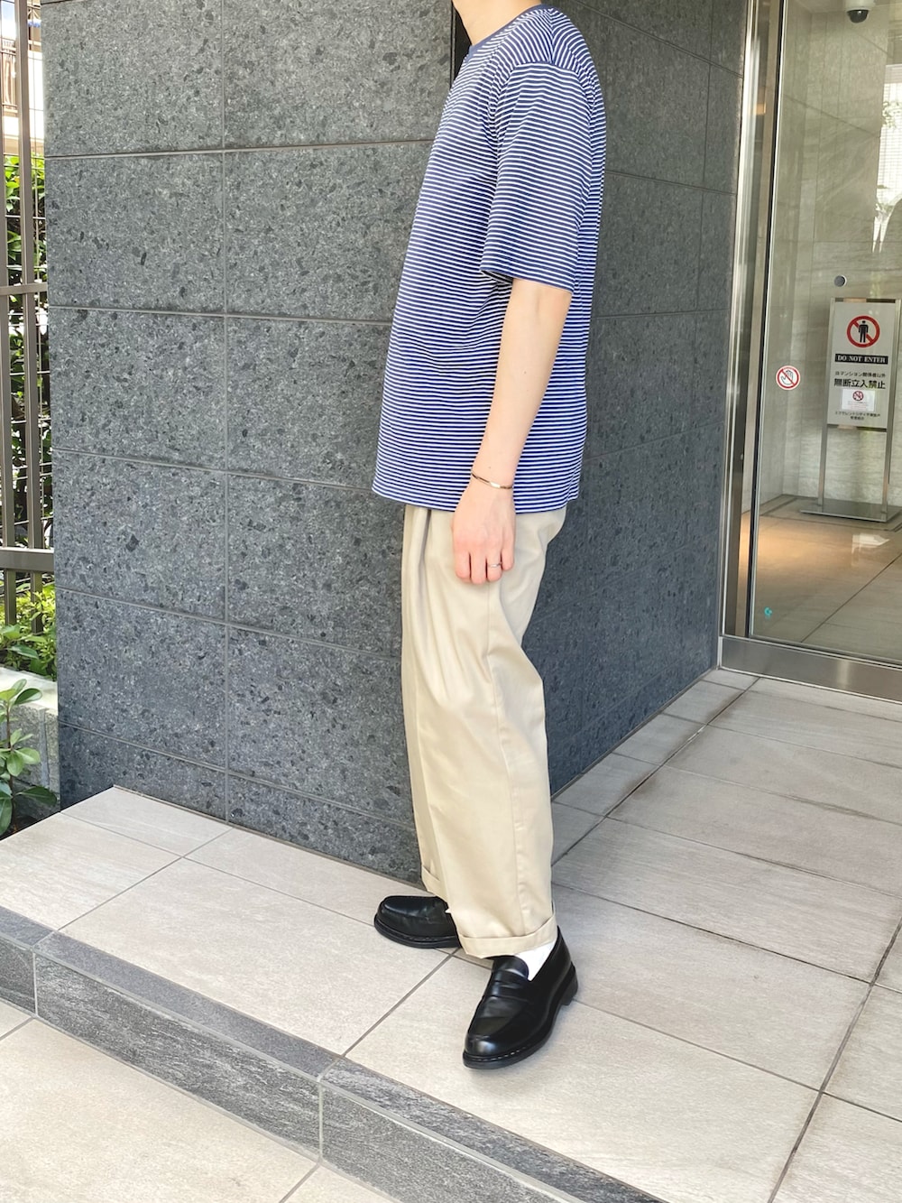 ブルー系のTシャツ/カットソー、ベージュ系のスラックス、ブラック系のローファーを着用したメンズの夏コーディネートの2枚目の写真