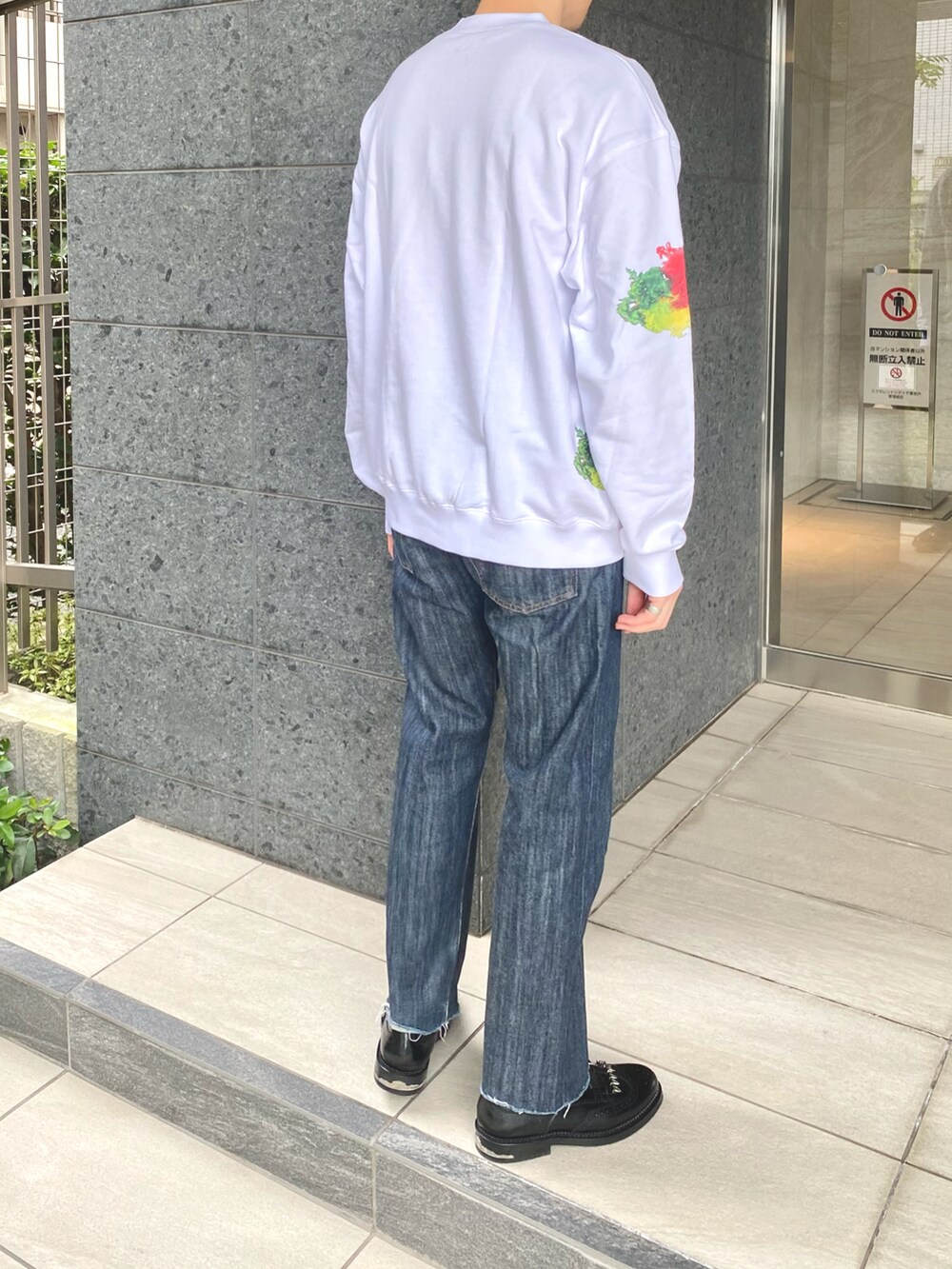 ホワイト系のスウェット、ブルー系のデニムパンツ、ブラック系のシューズを着用したメンズの秋コーディネートの2枚目の写真