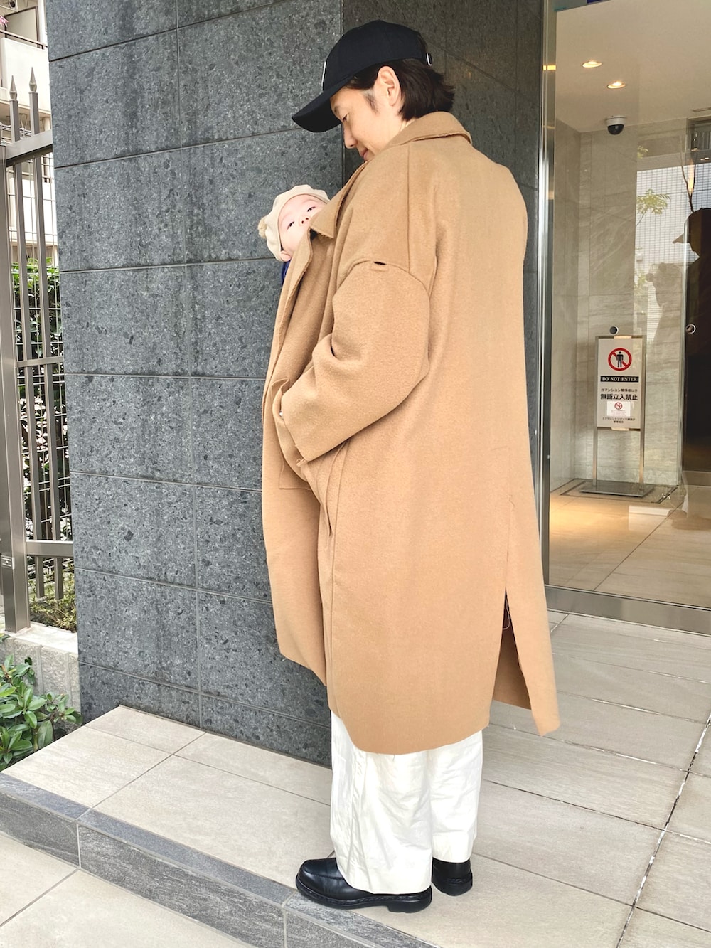 ベージュ系のトレンチコート、ホワイト系のパンツ、ブラック系のキャップを着用したメンズの冬コーディネートの3枚目の写真