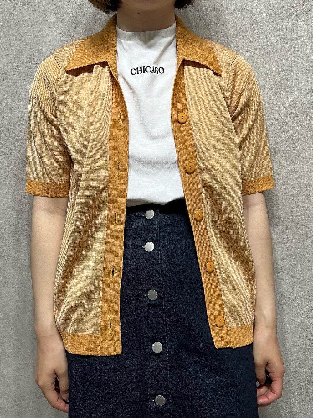 オレンジ系のカーディガン/ボレロを着用したレディースの春コーディネートの2枚目の写真