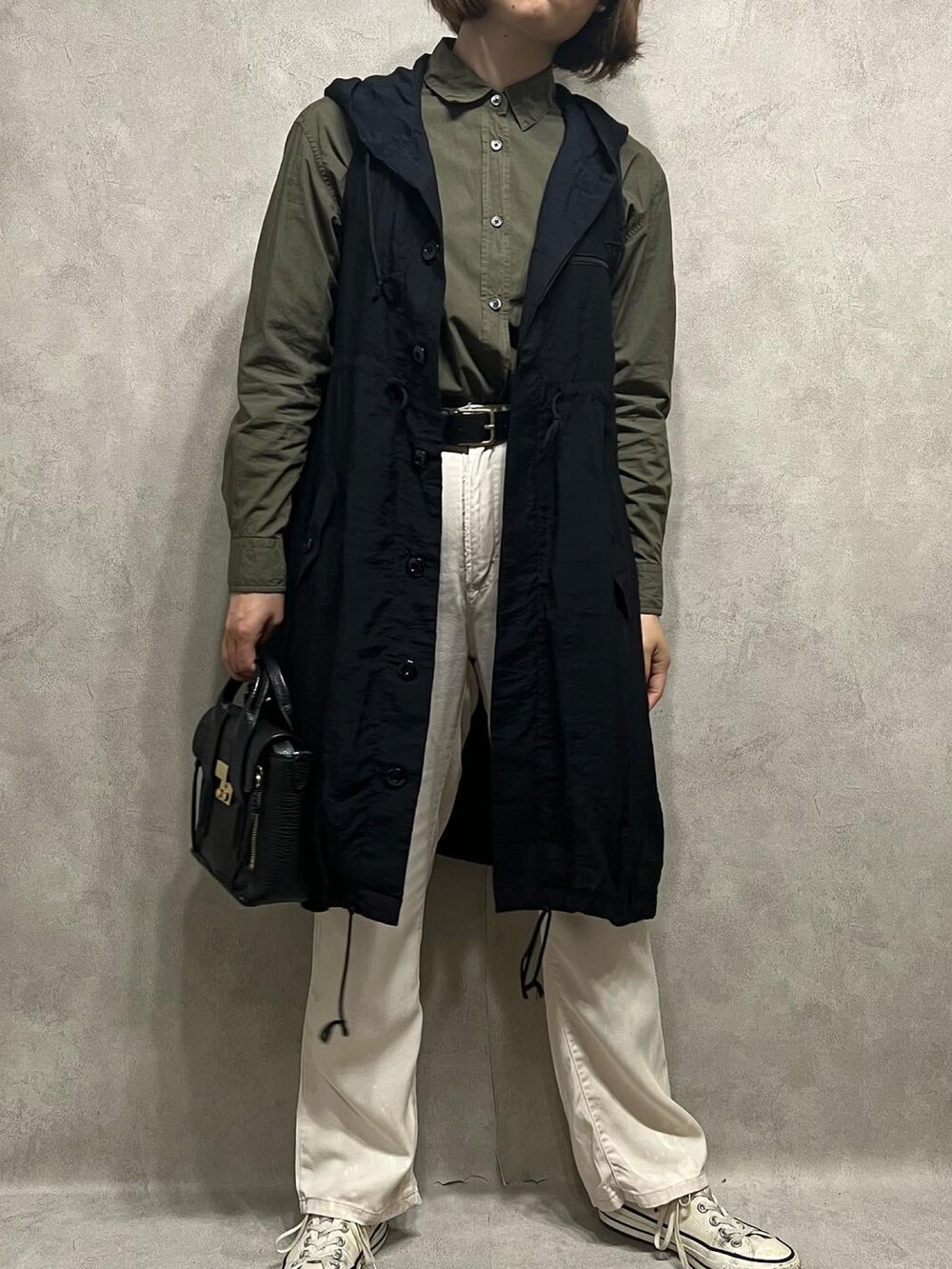 グリーン系のシャツ/ブラウス、ブラック系のベスト、ホワイト系のパンツを着用したレディースの春コーディネートの2枚目の写真