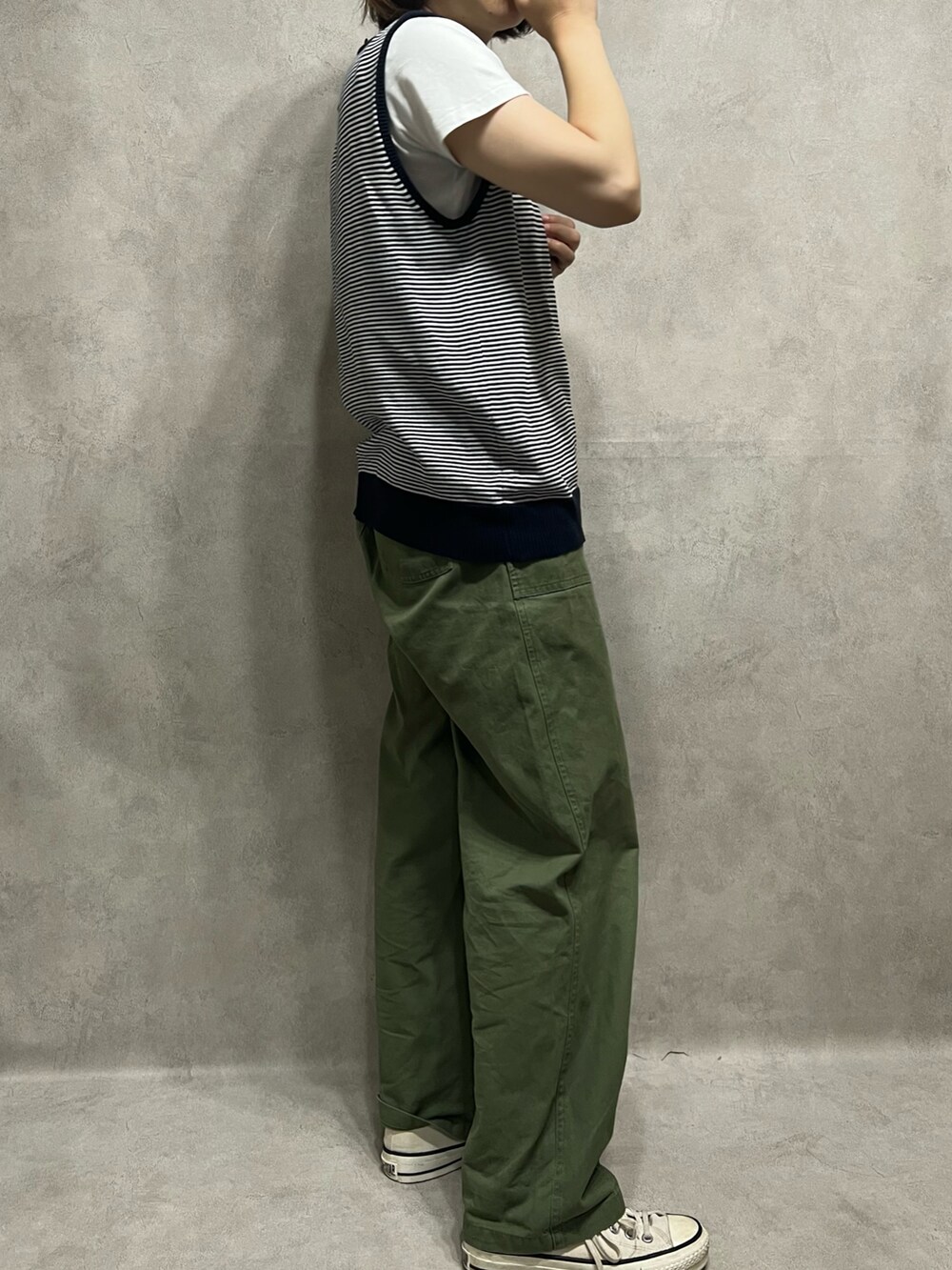 ブラック系のベスト、グリーン系のパンツ、ホワイト系のスニーカーを着用したレディースの夏コーディネートの2枚目の写真