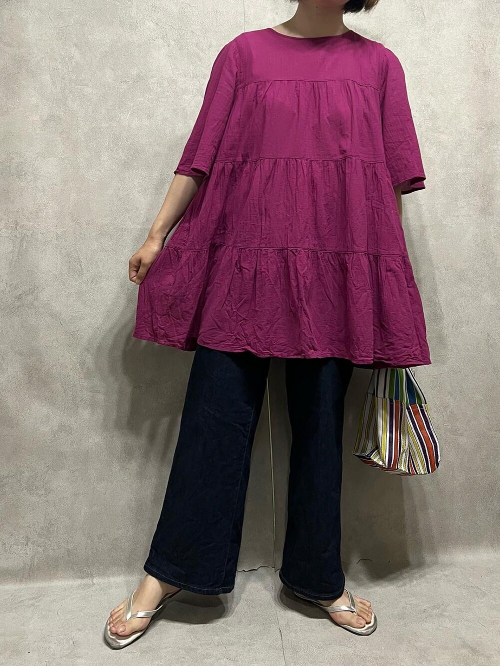 ピンク系のワンピース、ブルー系のデニムパンツを着用したレディースの春コーディネートの2枚目の写真