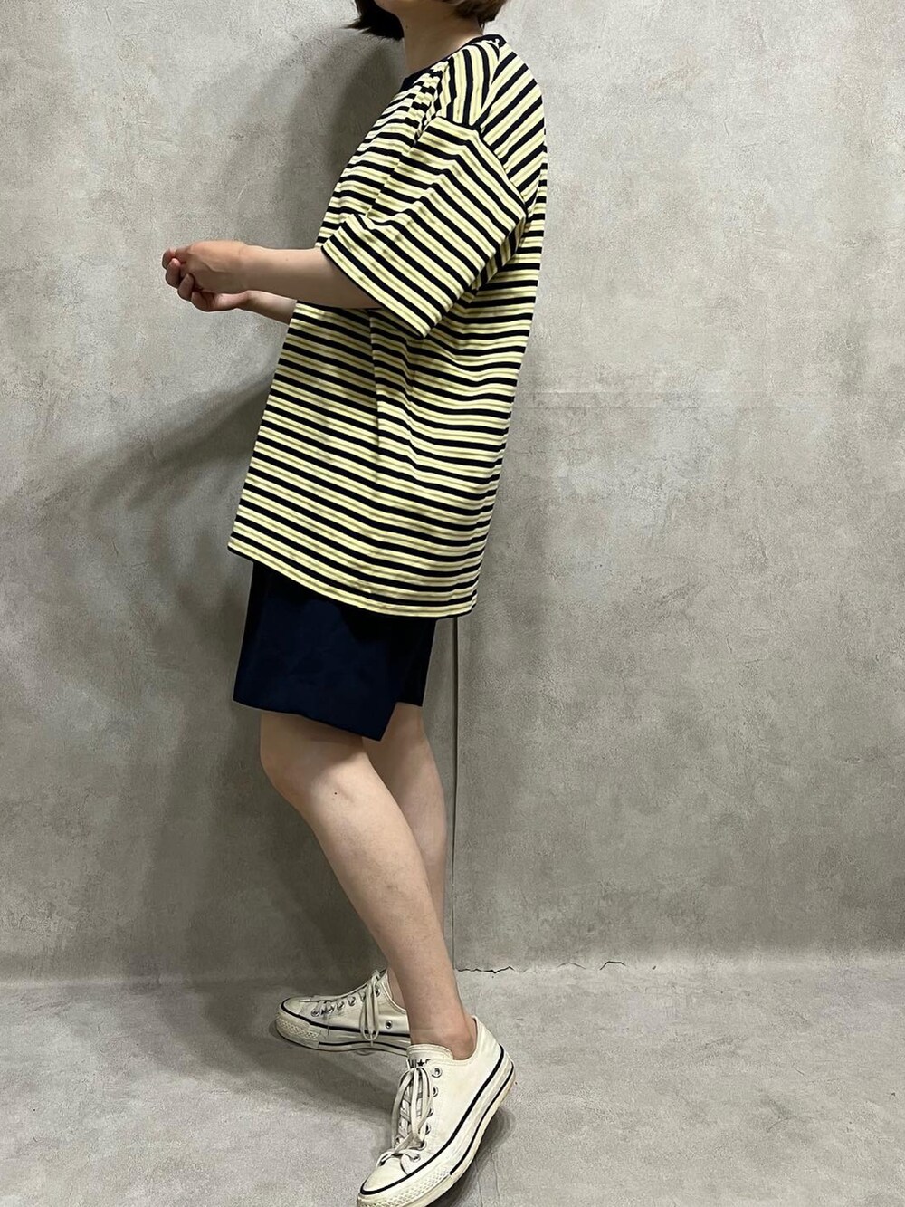 イエロー系のトップス、ブルー系のパンツ、ホワイト系のスニーカーを着用したレディースの夏コーディネートの2枚目の写真