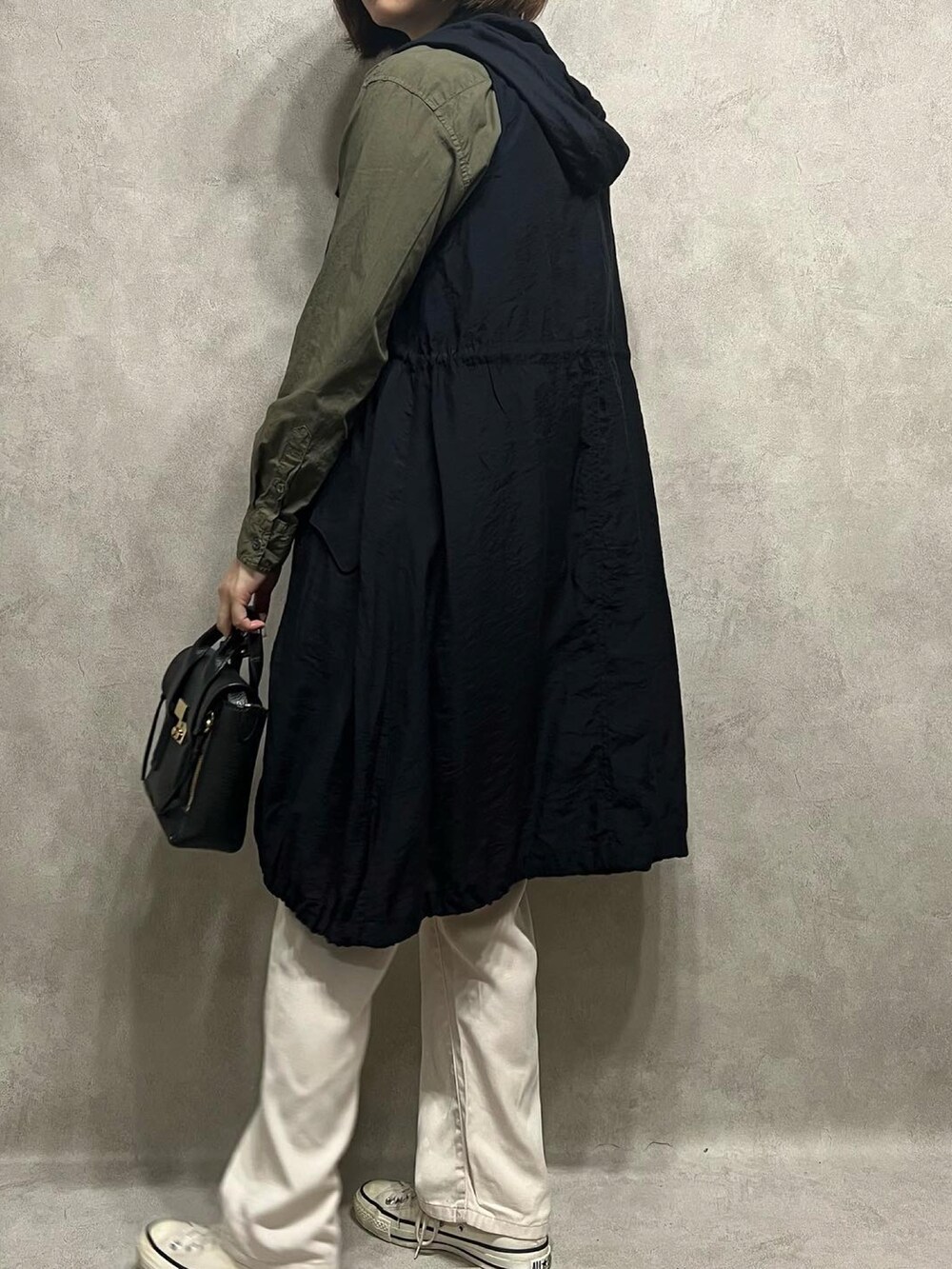 グリーン系のシャツ/ブラウス、ブラック系のベスト、ホワイト系のパンツを着用したレディースの春コーディネートの3枚目の写真